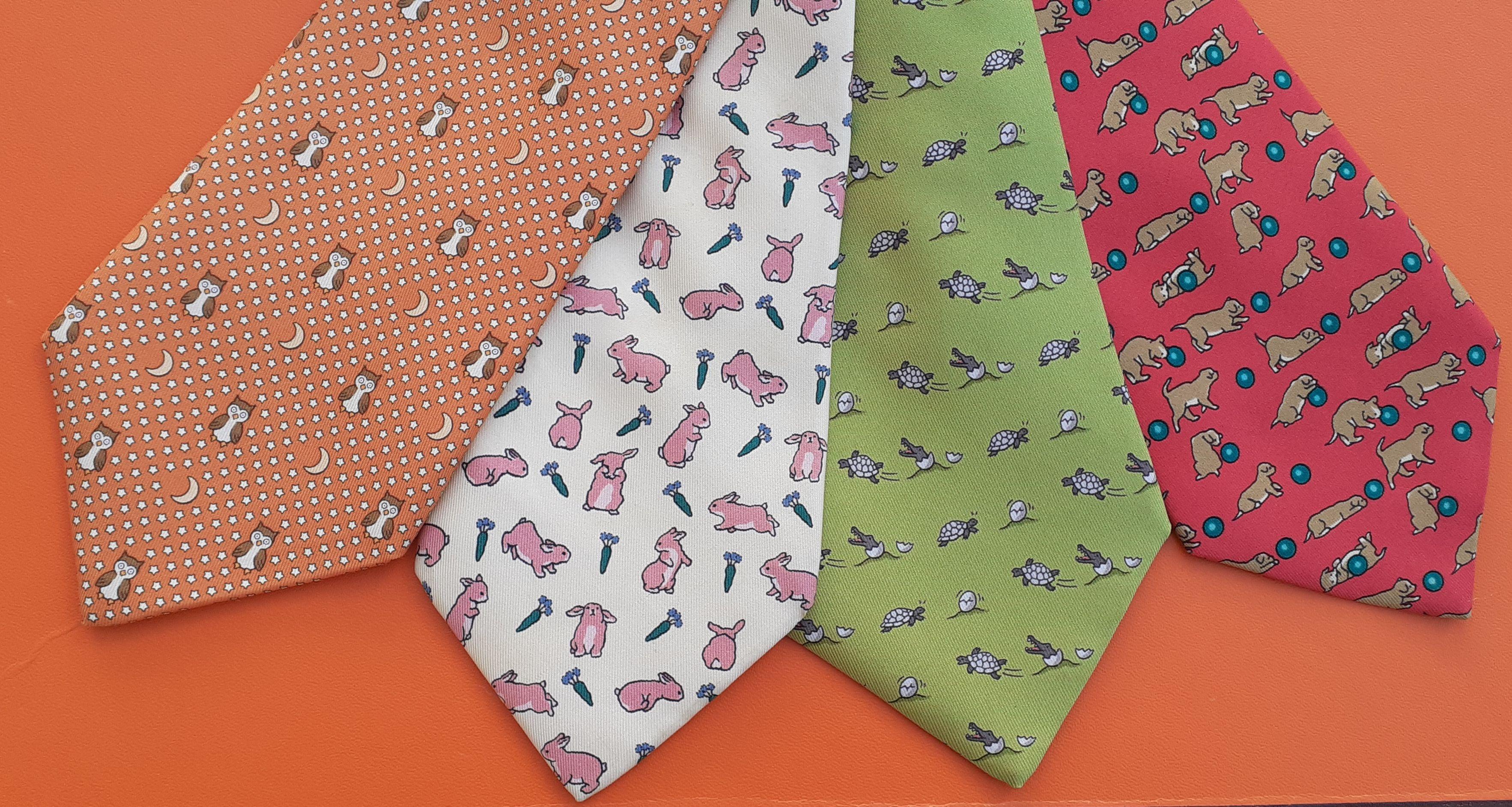 Cute Authentic Hermès Set of 4 Ties

Prints from left to right:

- 7997 EA: owls in a decor of stars and moon / Colorways: Orange, Brown, White, Yellow. Plain orange at back

- 7425 HA: rabbits and carrots / Colorways: Beige, Pink, Green. Plain