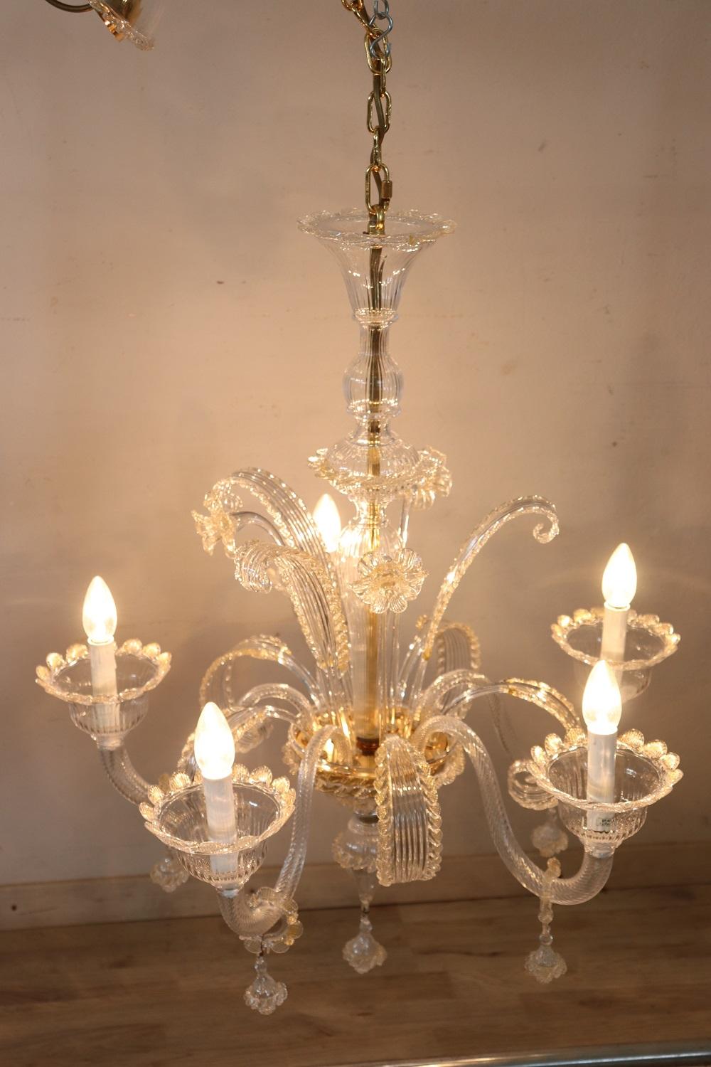 Beautiful and refined Italian 1980s Murano glass chandelier with five bulbs. The glass is clear with some gold powder decorations. This chandelier is characterized by extreme elegance and refinement, a multitude of flowers that stand out like a