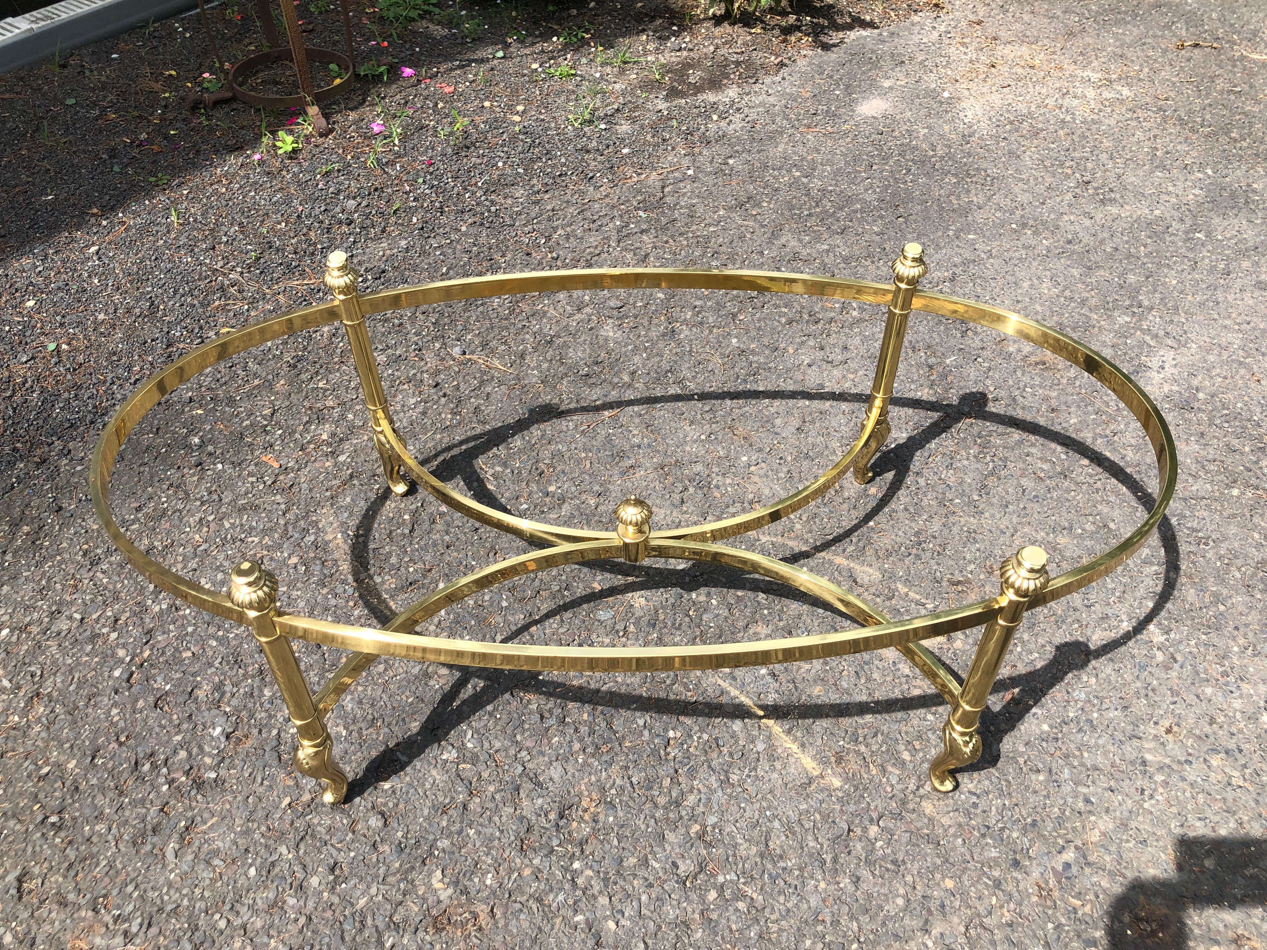 A lovely fine quality Hollywood Regency style brass and glass oval coffee table, attributed to La Barge.  This table has a beveled glass top, rising on finial topped X-form cross-stretcher base, ending on shell accented cabriole legs. circa 1970s. 