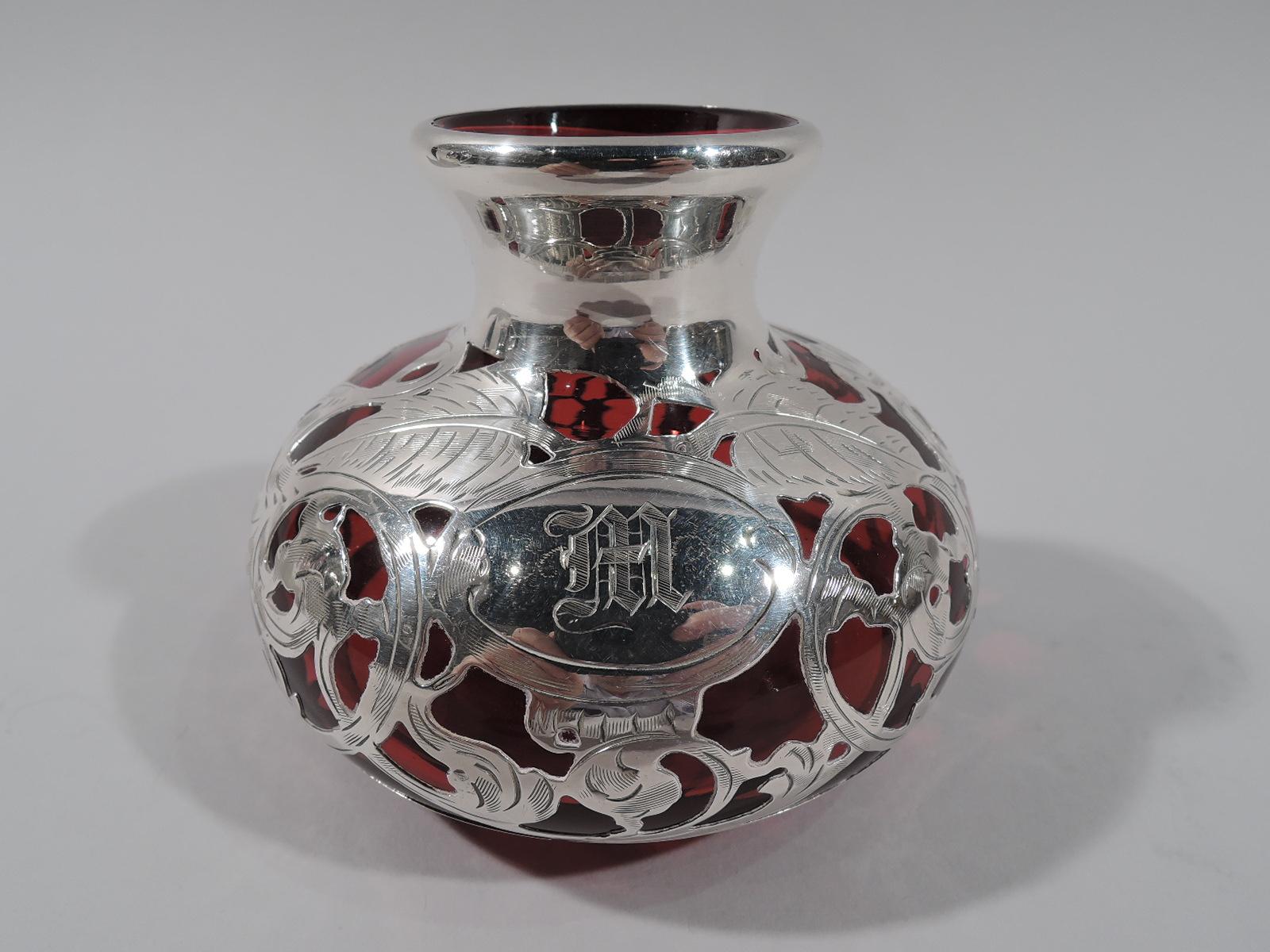 Lovely turn-of-the-century red glass bud vase with engraved silver overlay. Made by La Pierre in New York. Bellied bowl with short neck and flared rim. Dense overlay in form of rinceaux with leaves and flowerheads. Oval frame engraved with shaded