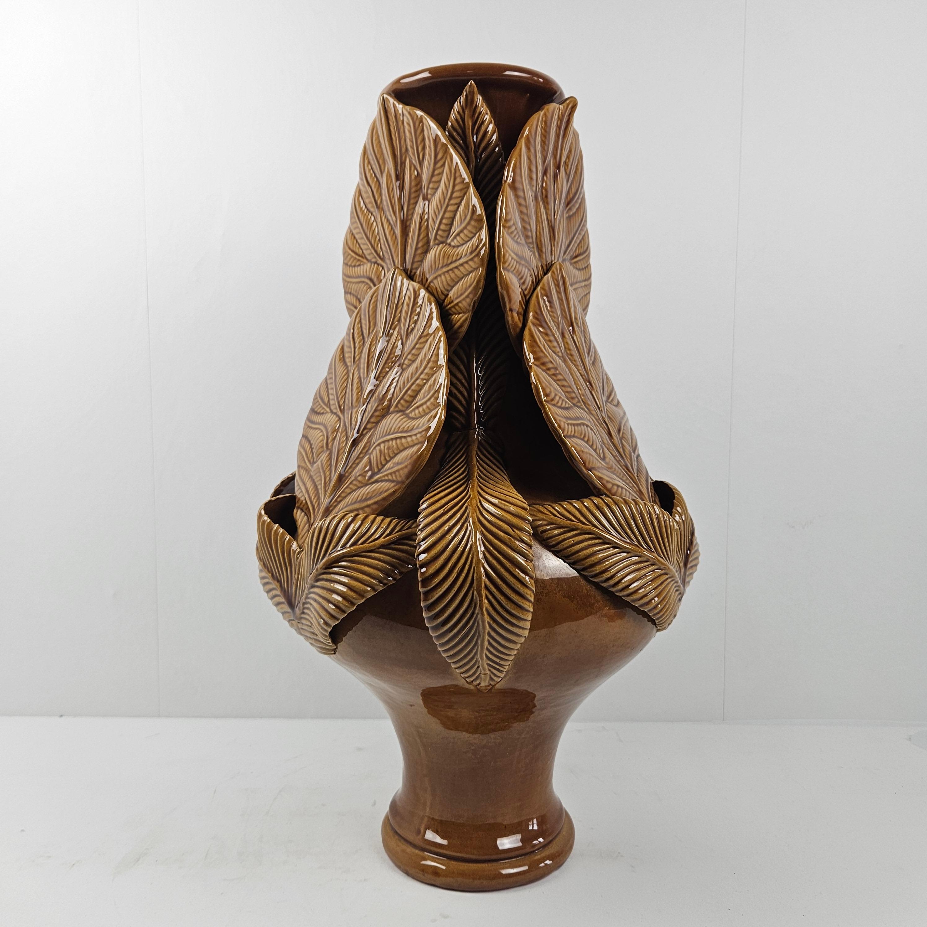 Amazing and large ceramic vase, fabricated in Italy in the 80's.

Beautiful design with different kind of leaves and a slender lower part.
Finished with a deep brown glazed finish with different tone.

We have never seen this vase or something