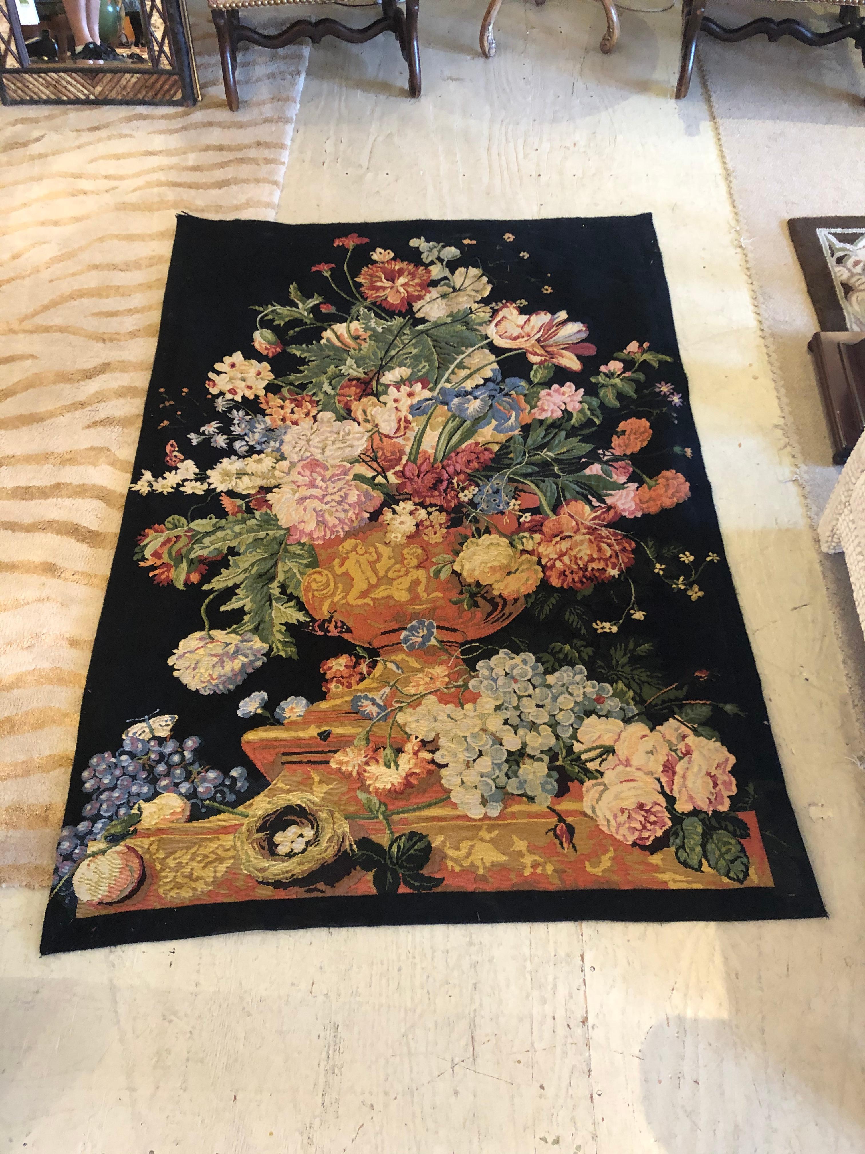 A striking French tapestry having black background and gorgeous rich floral in gold, blue, pink and green. There's a rod opening at the top for easy hanging.