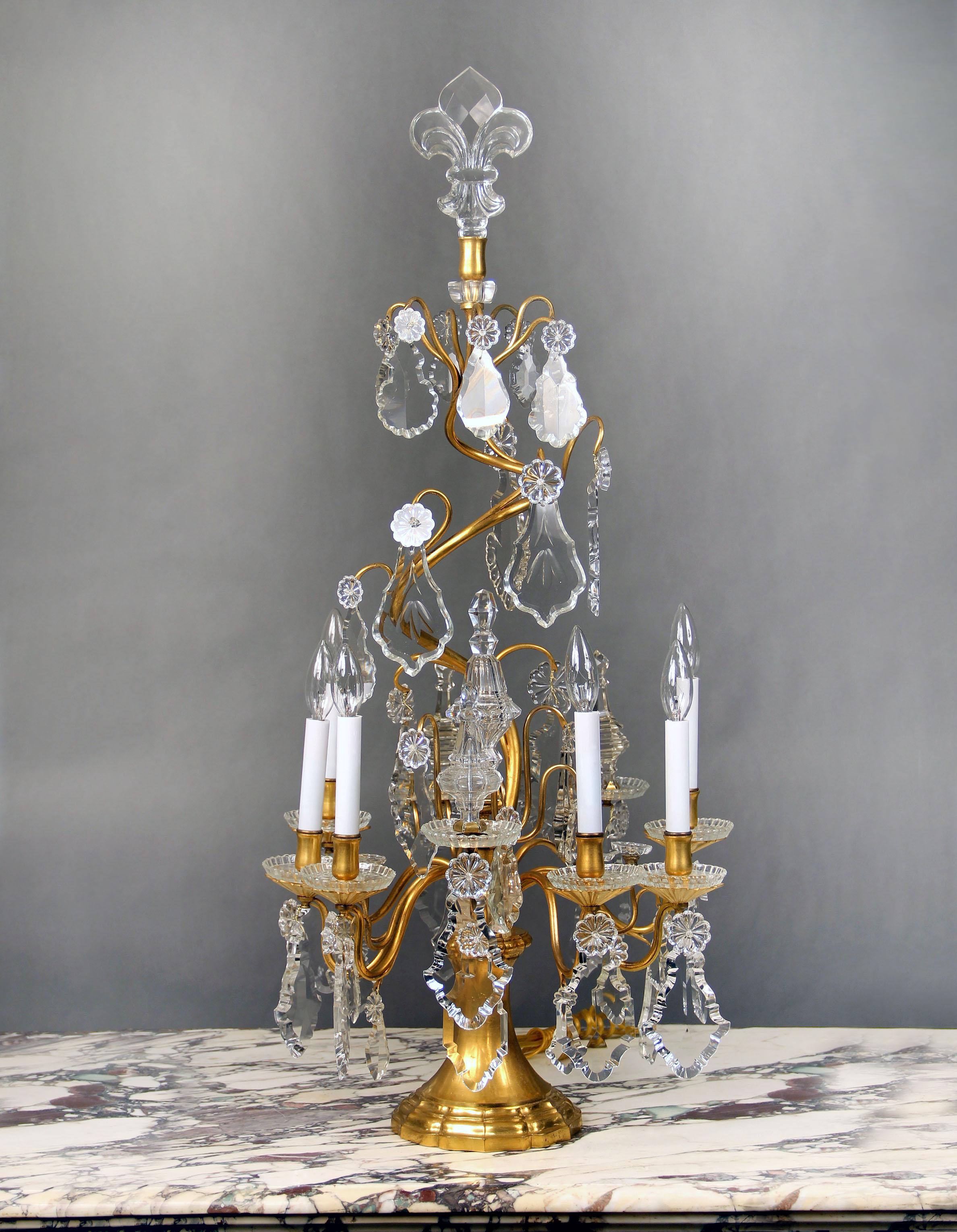 A Lovely Late 19th Century Gilt Bronze and Baccarat Crystal Six Light Girandole

Multi-faceted and shaped crystal, bronze spiral central column, four spears, six perimeter lights, bobeche cups, topped off with a crystal Fleur de lis.