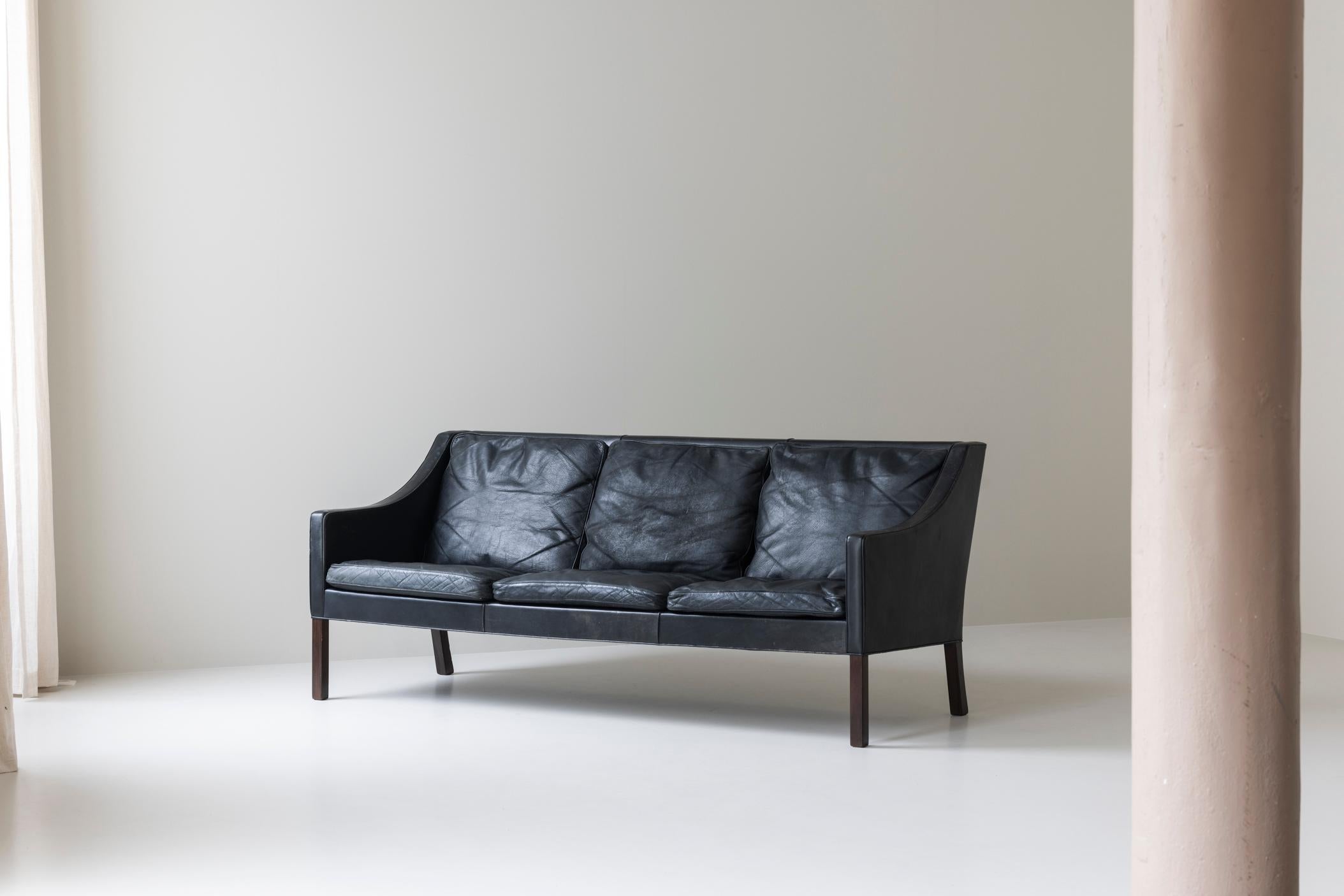 Charmant canapé trois places conçu par Børge Mogensen pour Fredericia, Danemark 1963. Il s'agit du modèle 2209, dont la sellerie en cuir noir d'origine a été magnifiquement vieillie au fil des ans, ce qui lui confère une riche patine. Les élégants