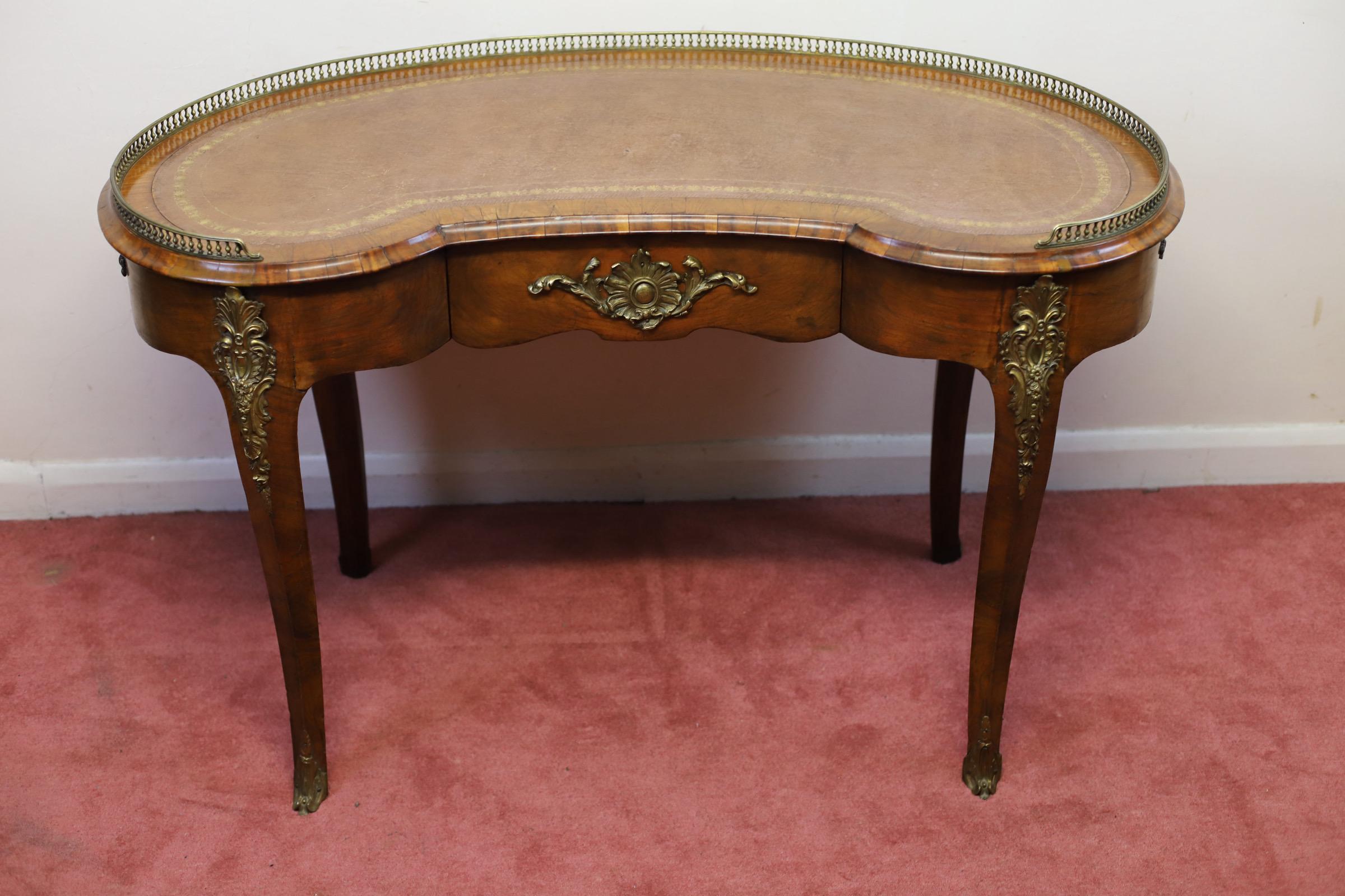 We delight to offer for sake this lovely antique walnut and gilt metal mounted kidney shaped writing table in Louis XV style, late 19th century; the top with inset gilt tooled leather skiver within a three quarter balustraded brass gallery; above a