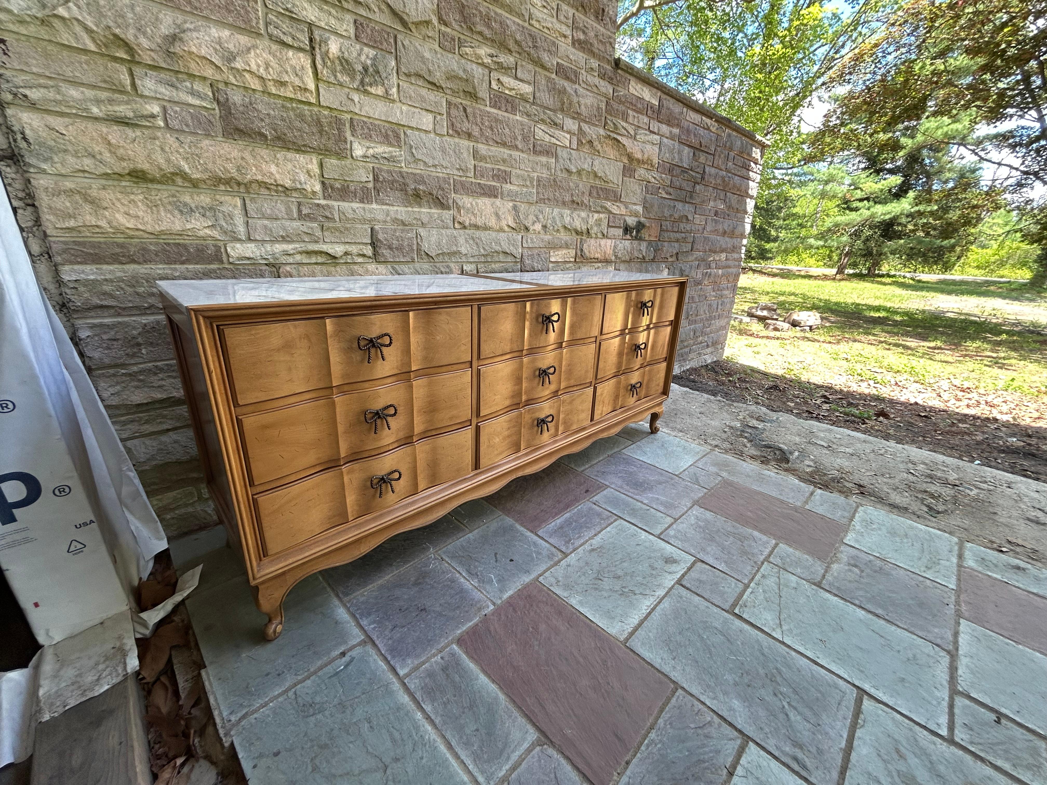 Preciosa cómoda/credenza larga de estilo Regencia Provincial Francés con encimera de mármol blanco y bonitos tiradores de lazo para los cajones. Nos encanta todo lo relacionado con esta pieza inusual y bien elaborada de American of Martinsville.
Las