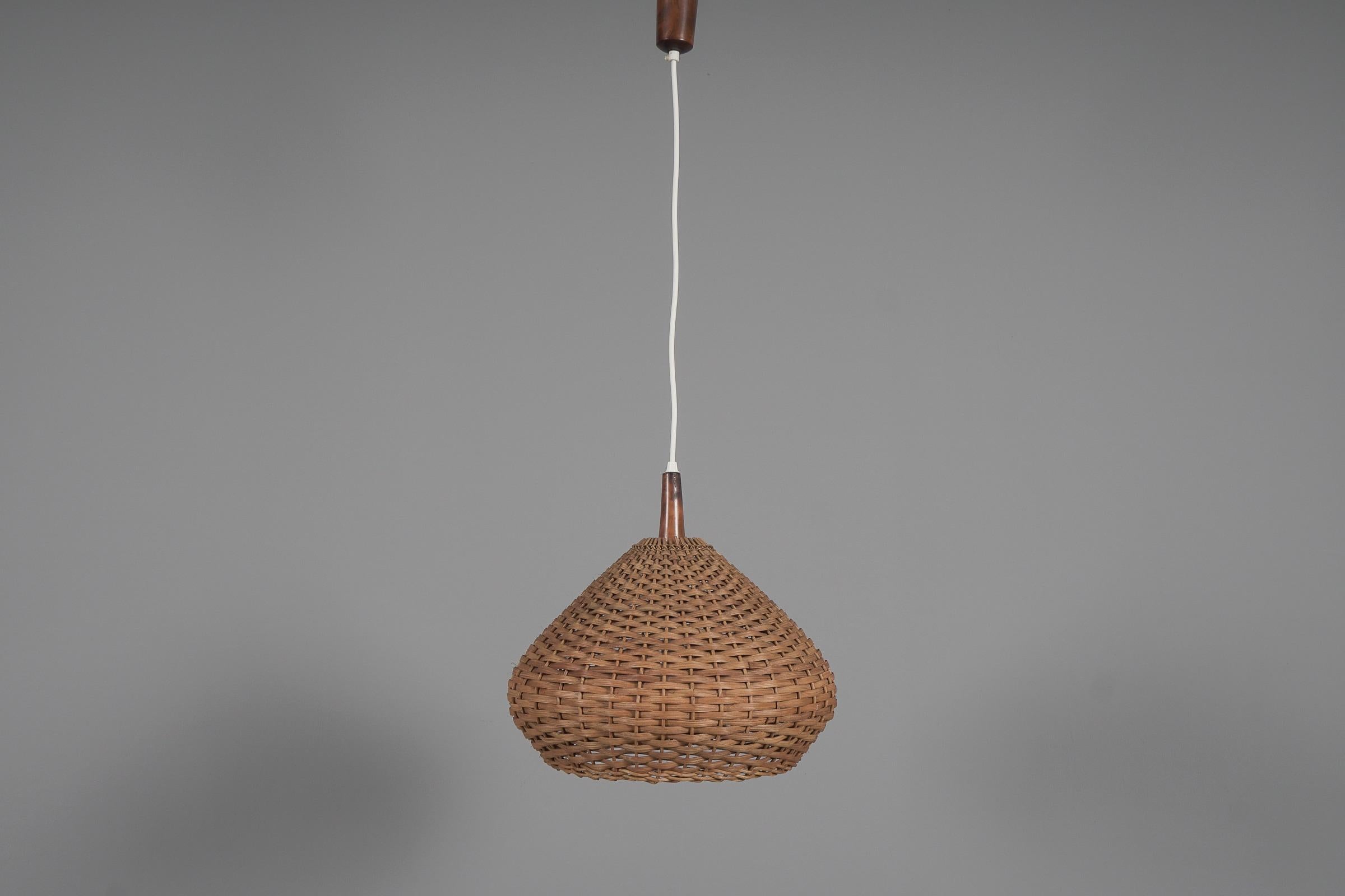 Rare and lovely decorative Mid-Century Modern pendant lamp. Designed and manufactured probably in Scandinavia, 1960s.

The lamp can be adjusted up to 50cm height.

Executed in rattan and wood, the pendant lamp comes with 1 x E27 / E26 Edison