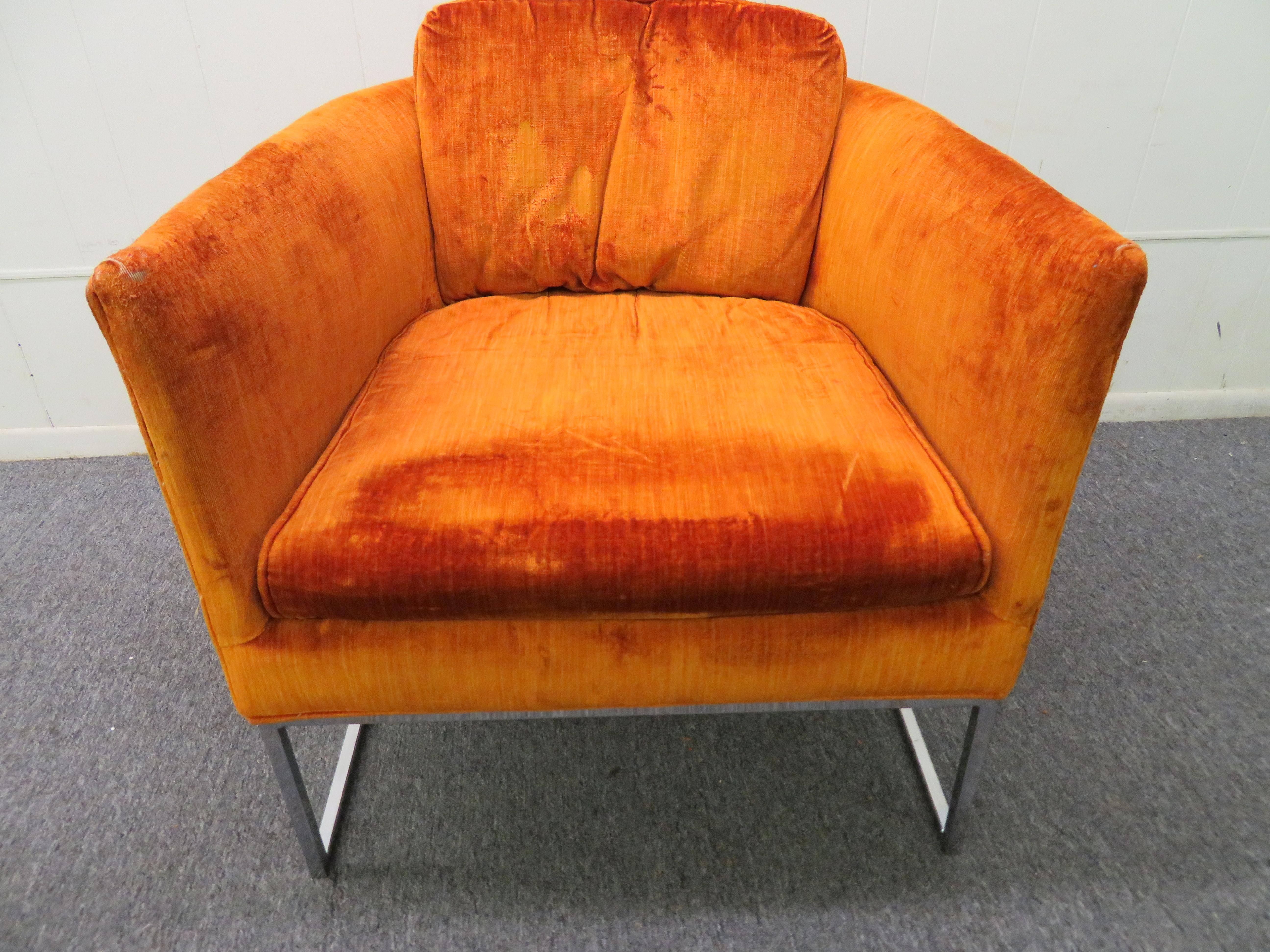 Joli fauteuil de salon à dossier baril et cadre fin chromé, style Milo Baughman. Cette chaise a conservé son velours orange d'origine qui présente des signes d'usure. Il est recommandé de la rembourrer à nouveau. Nous aimons la délicate base chromée