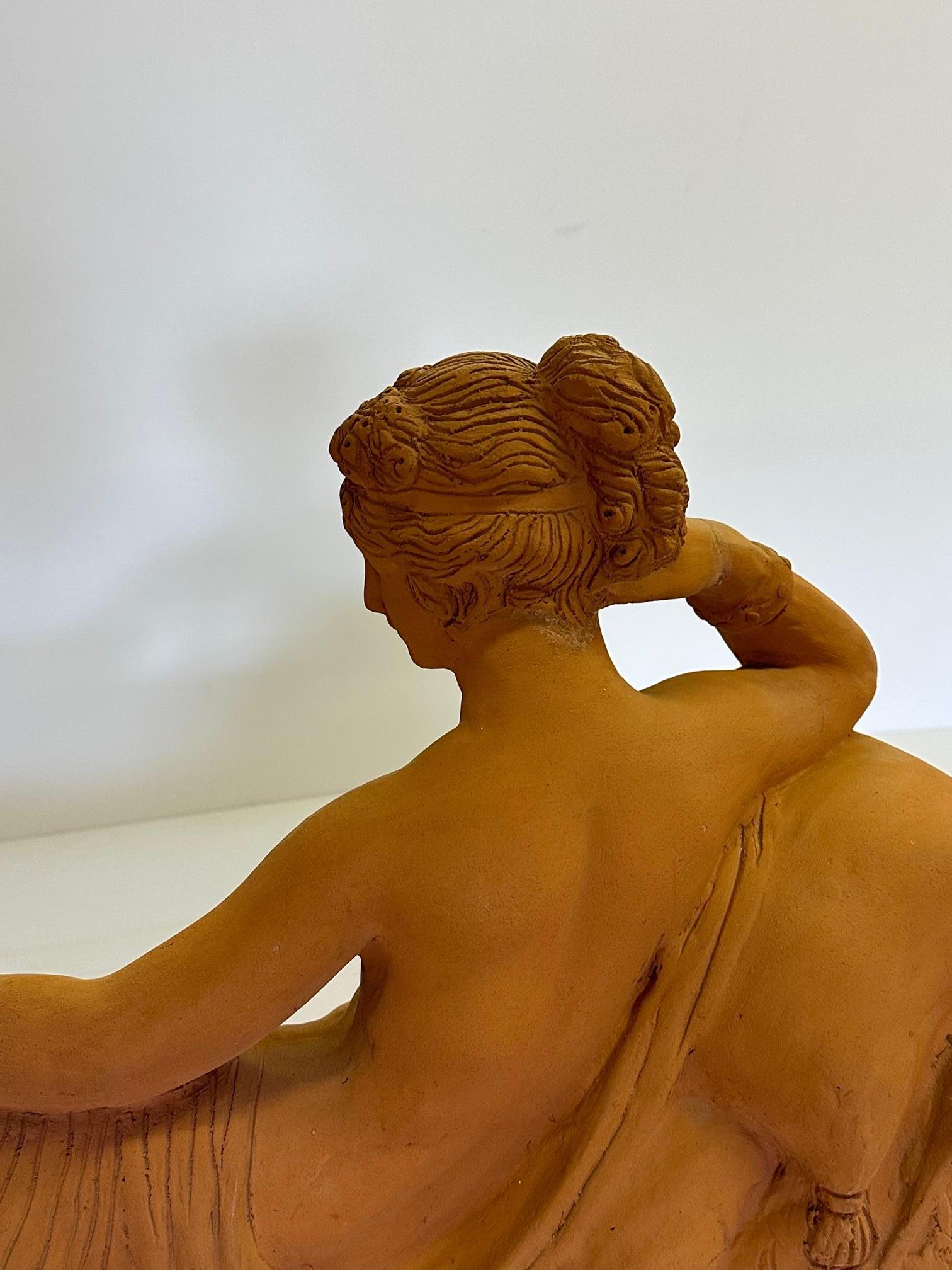 Stunning and romantic terracotta figural sculpture of a classical beauty reclining partly disrobed on a chaise. Her pose and pretty face are serene and very sexy.
