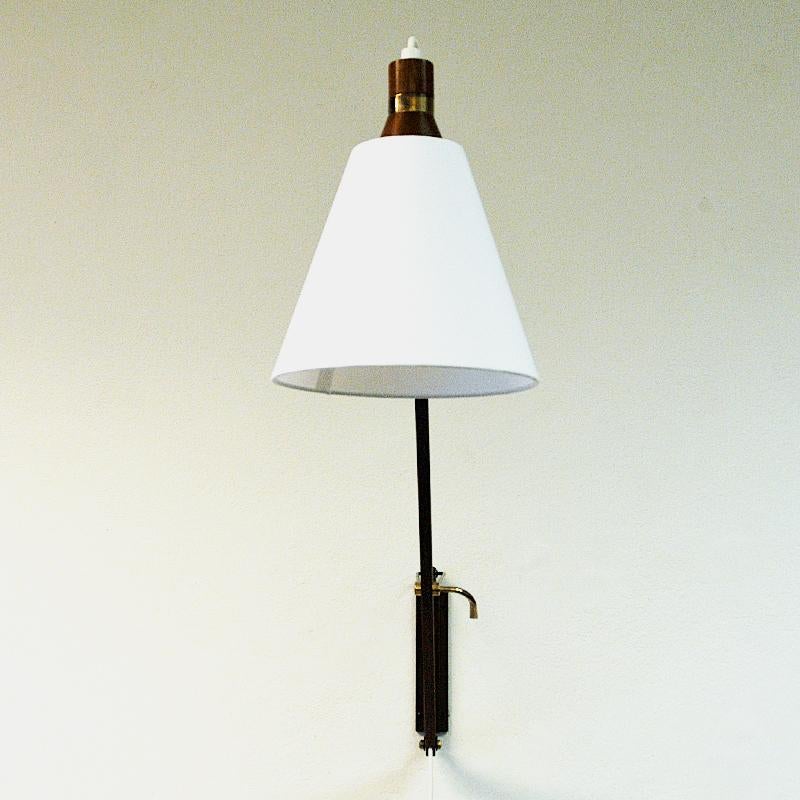 Mid-century wall lamp on an adjustable teak arm including a white fabric shade by T. Røste & Co Norway 1950s. The lamp can be adjusted to the left, right, upwards, downwards and straight ahead. A great lamp for all walls and all rooms. Perfect for
