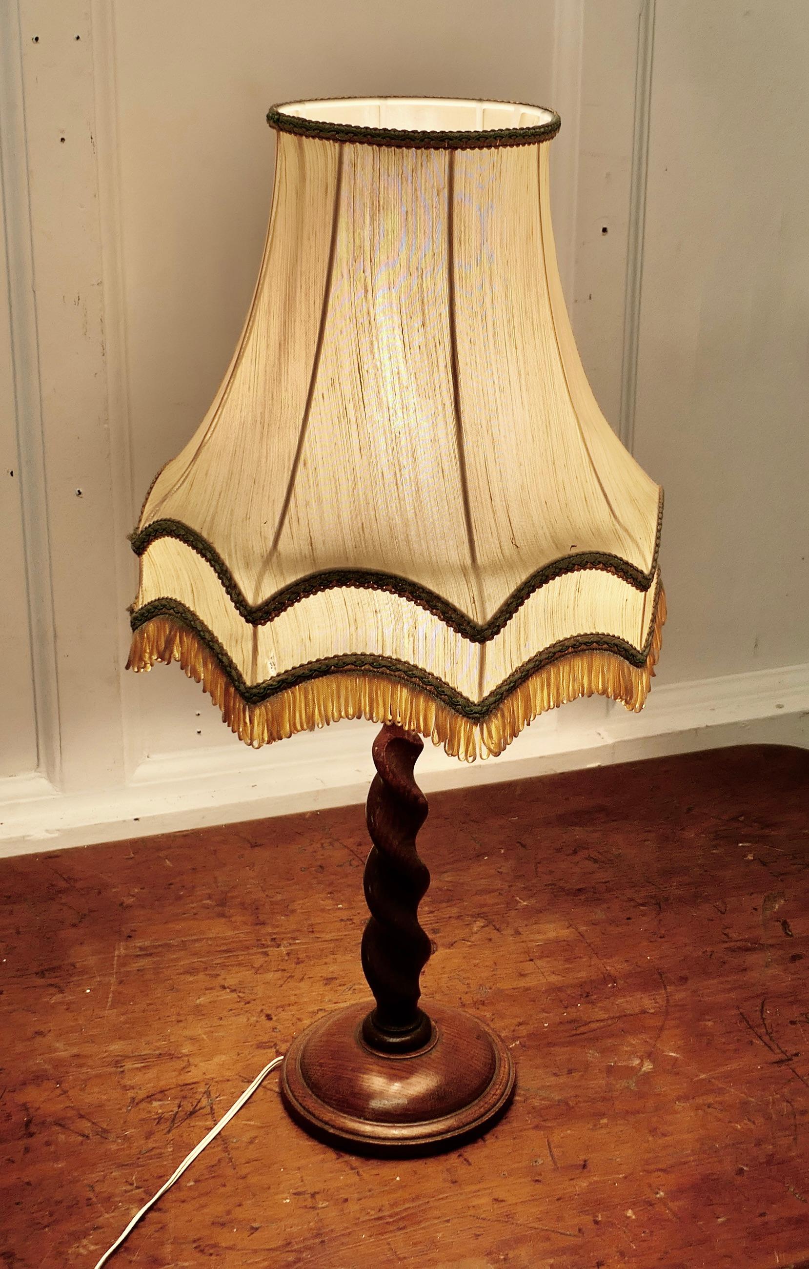 Lovely Oak Turned Barley Twist Table Lamp

 A skilfully turned piece of Oak, this lamp stands on a turned wooden base, it is in good condition, the lamp is working and comes with a very attractive shade but this is used and has a few snags 
The lamp