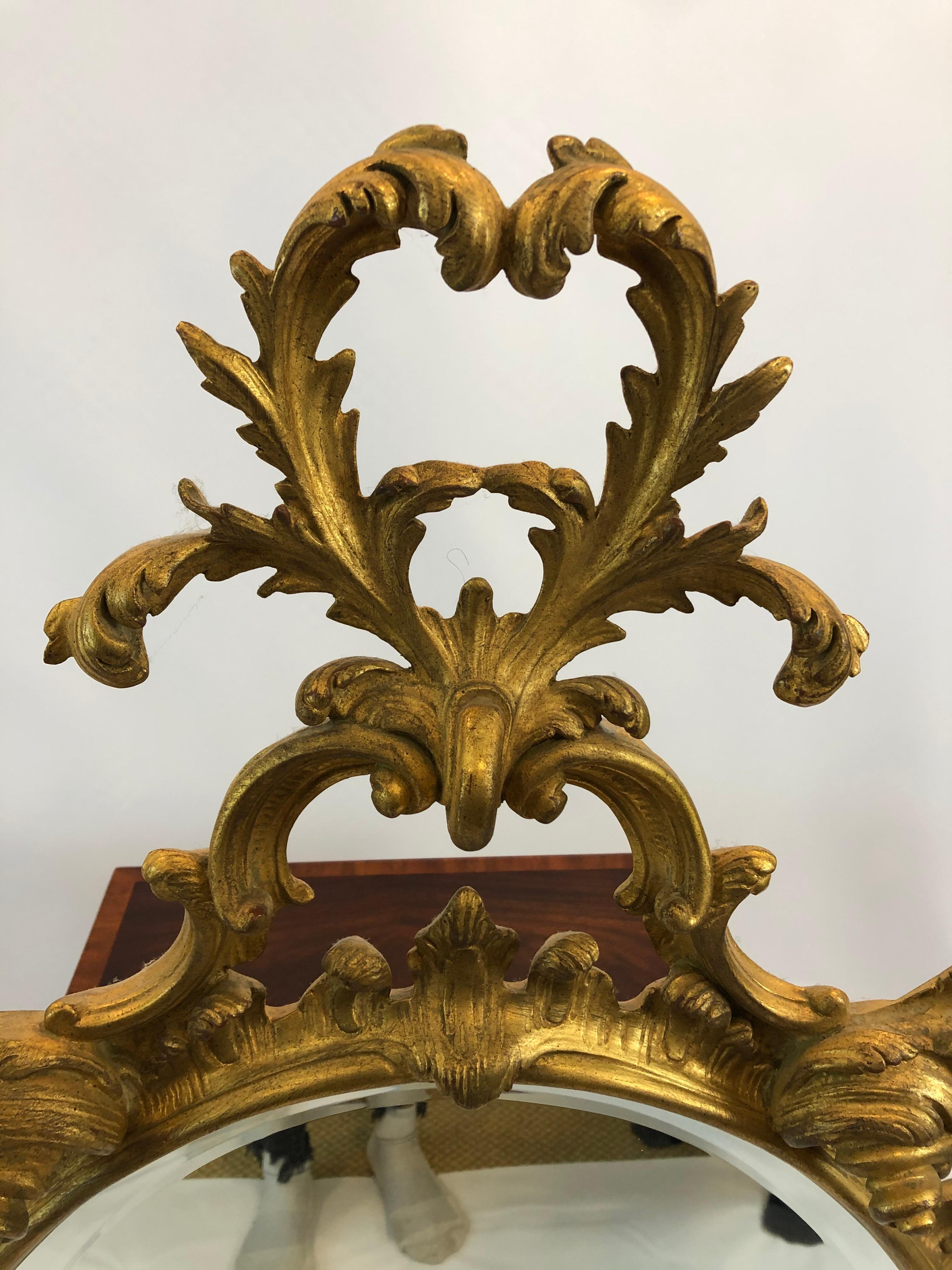 Ornately carved giltwood oval French style mirror having heart shaped adornment on top and marvelous flame embellishments around the periphery.