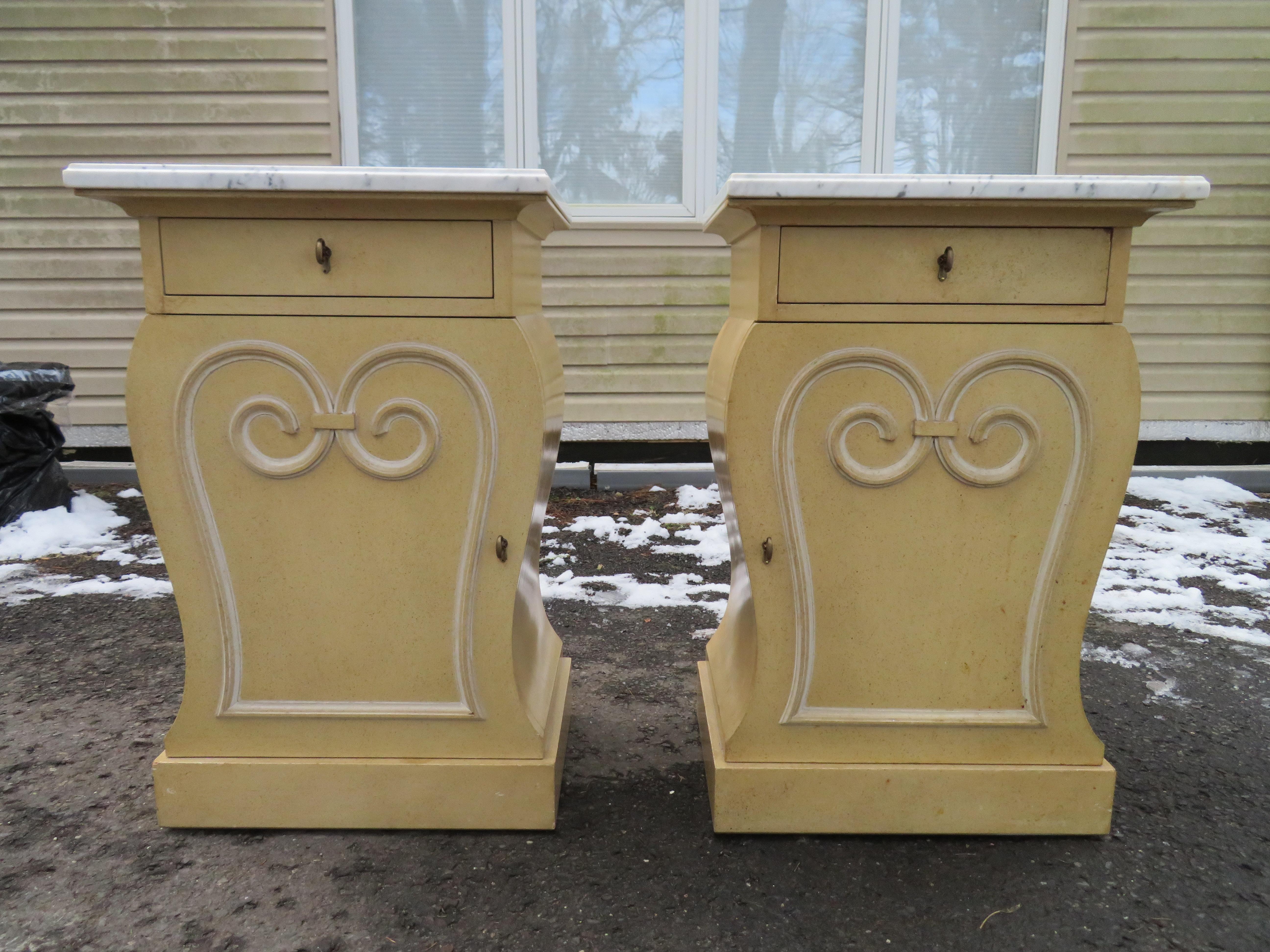 This gorgeous pair of Hollywood Art Deco end tables or nightstands was realized by the esteemed American producer Grosfeld House, circa 1945. They have a raised scroll design in the center of each cabinet panel, which is repeated in the sinuous