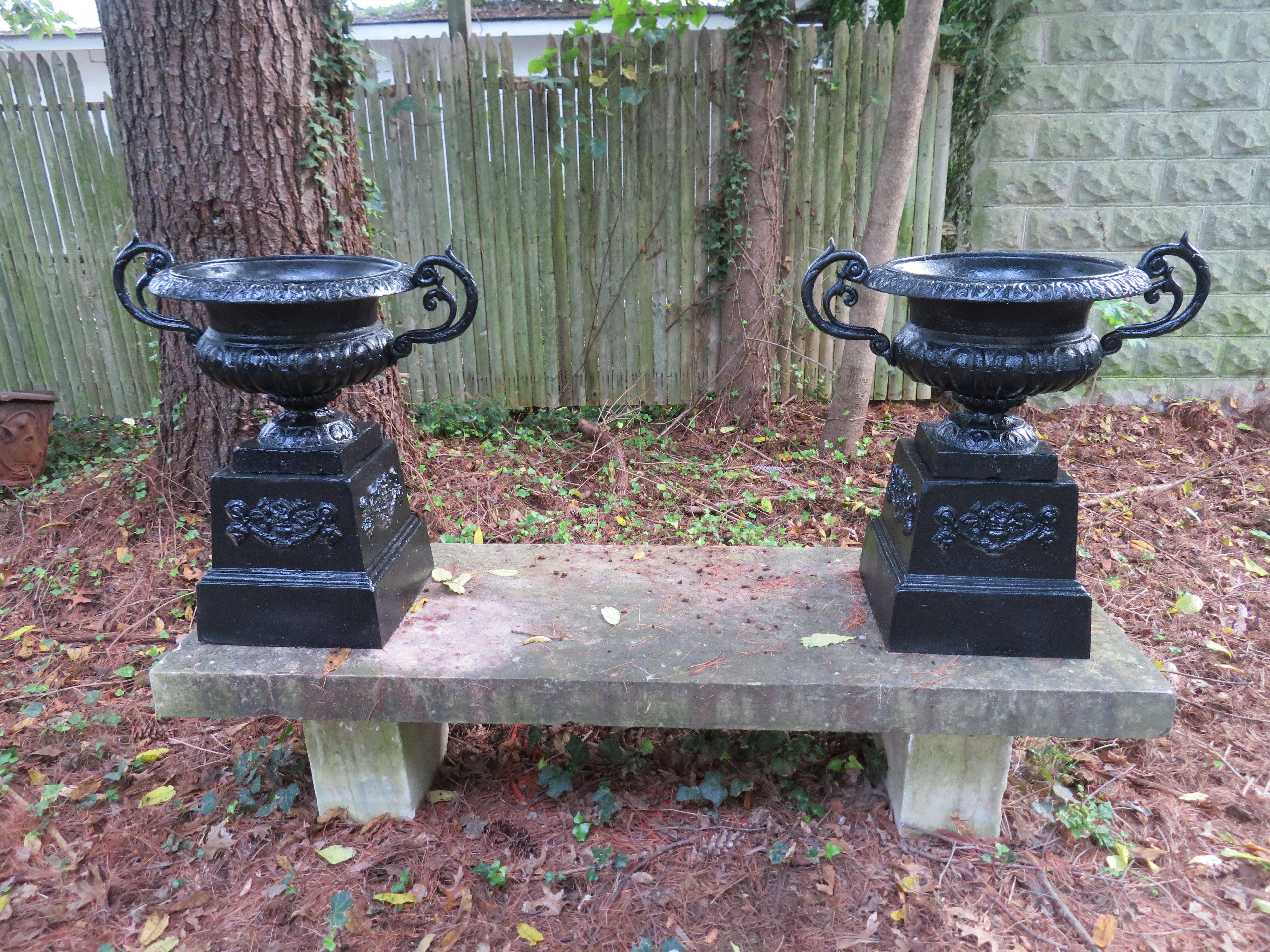 Lovely pair of cast iron vintage Victorian style urns from the midcentury. Urns have a fresh coat of black paint and are ready to place right into your garden.
