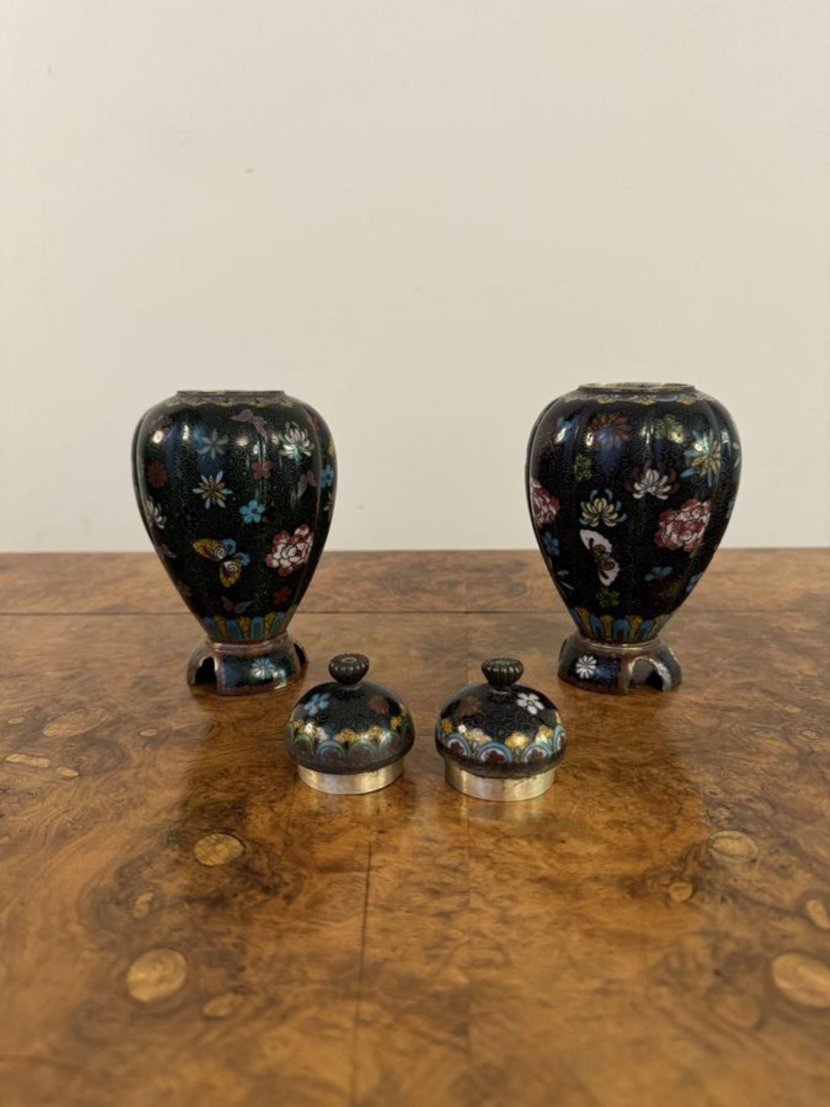 Lovely pair of antique cloisonne lidded vases, having a lovely pair of antique cloisonné lidded vases decorated with beautiful flowers in blue, red, yellow, green and white colours with the original lids and finales raised on shaped bases.

D. 1900