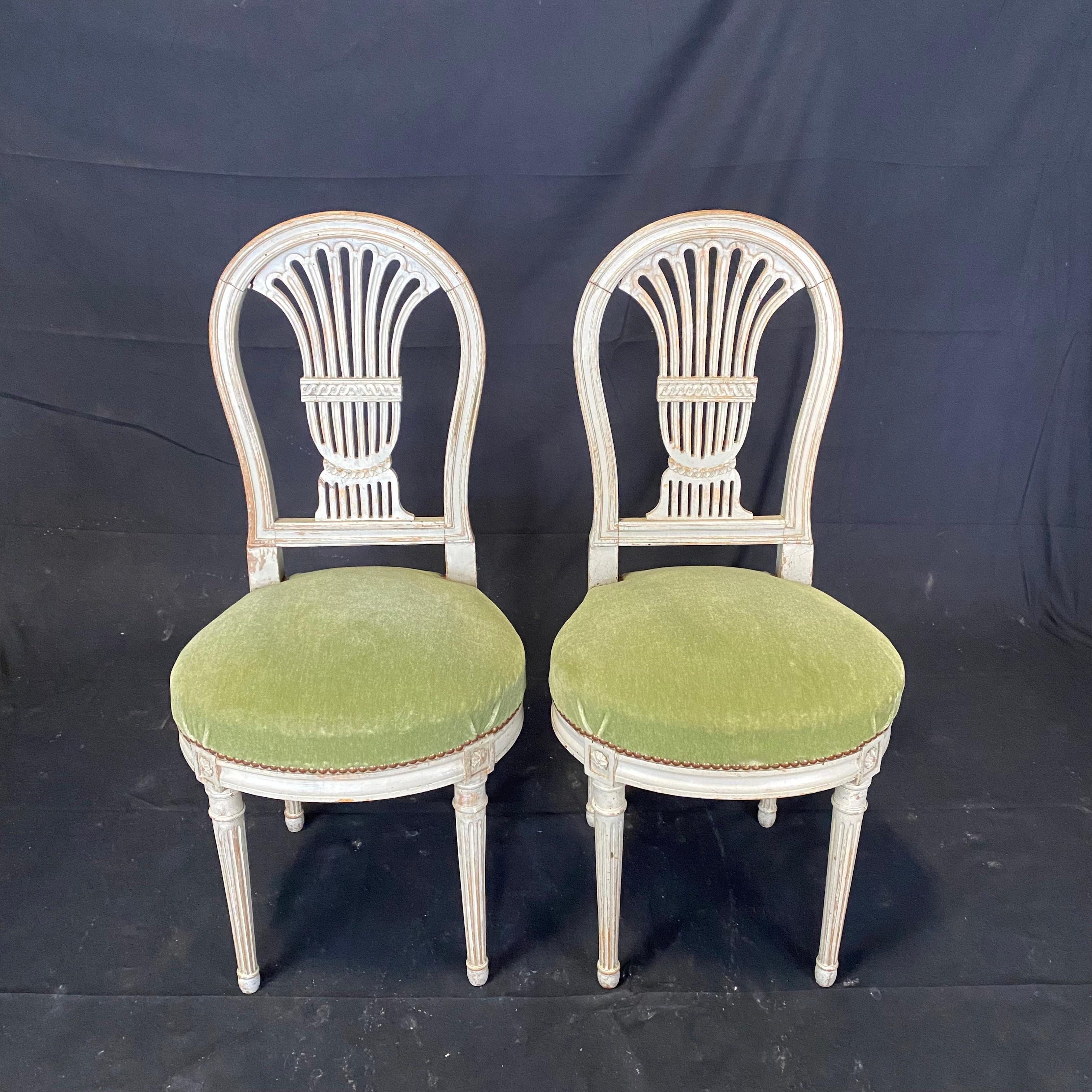 Really lovely pair of antique French Louis XVI dining room chairs with harp or balloon shaped ornament in the back, the legs decorated with fluting and rosettes, and the wood with original ivory paint. Fabulous green mohair upholstery. #6153.
