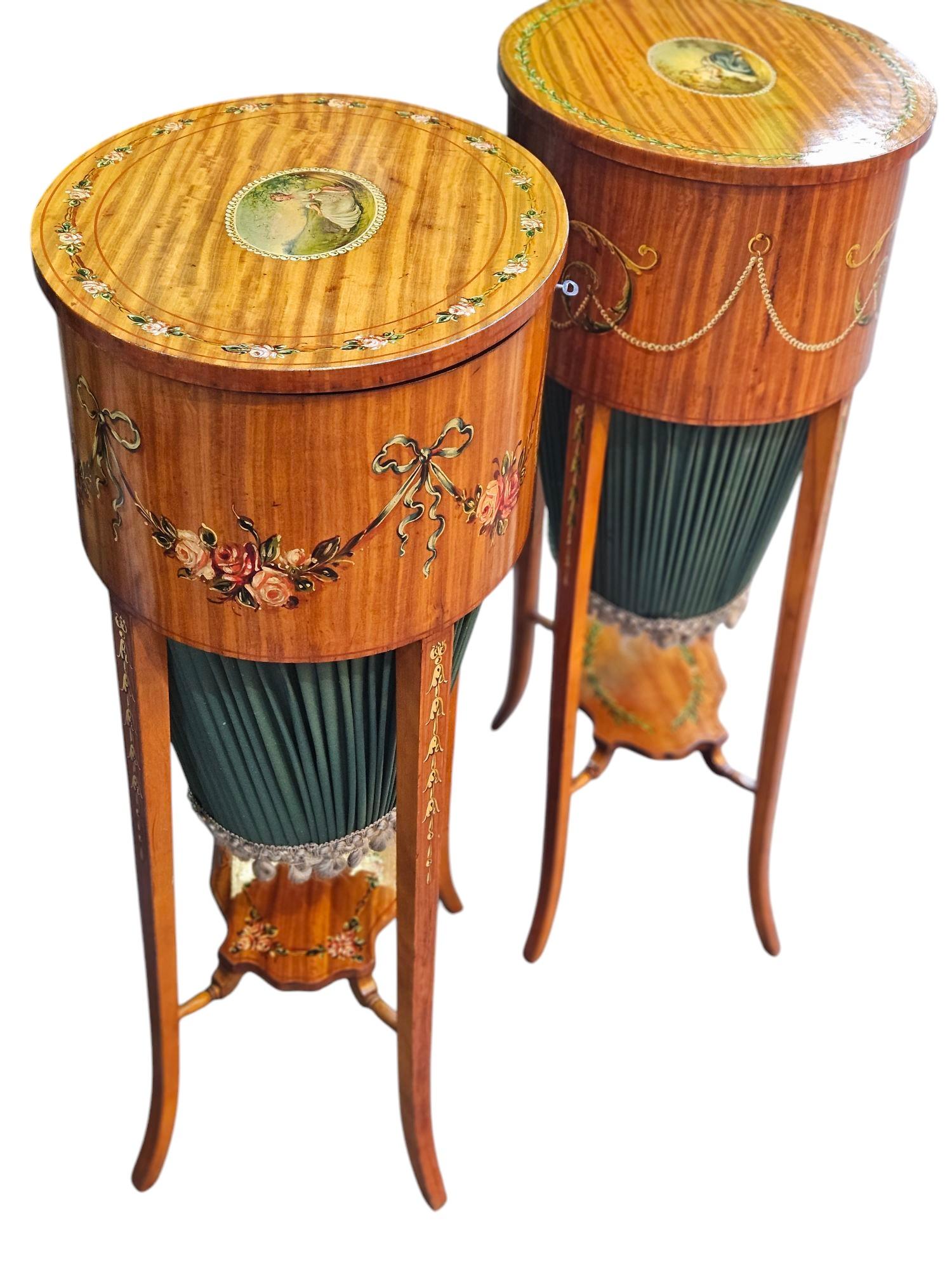 Paire de tables à coudre en bois de satin, plateau rond ovale, boîte à ouvrage à l'intérieur 
Décoration florale peinte à la main
Debout sur trois pattes uni par un brancard peint
Ces tables ont été délicatement repolies et sont prêtes à l'emploi.