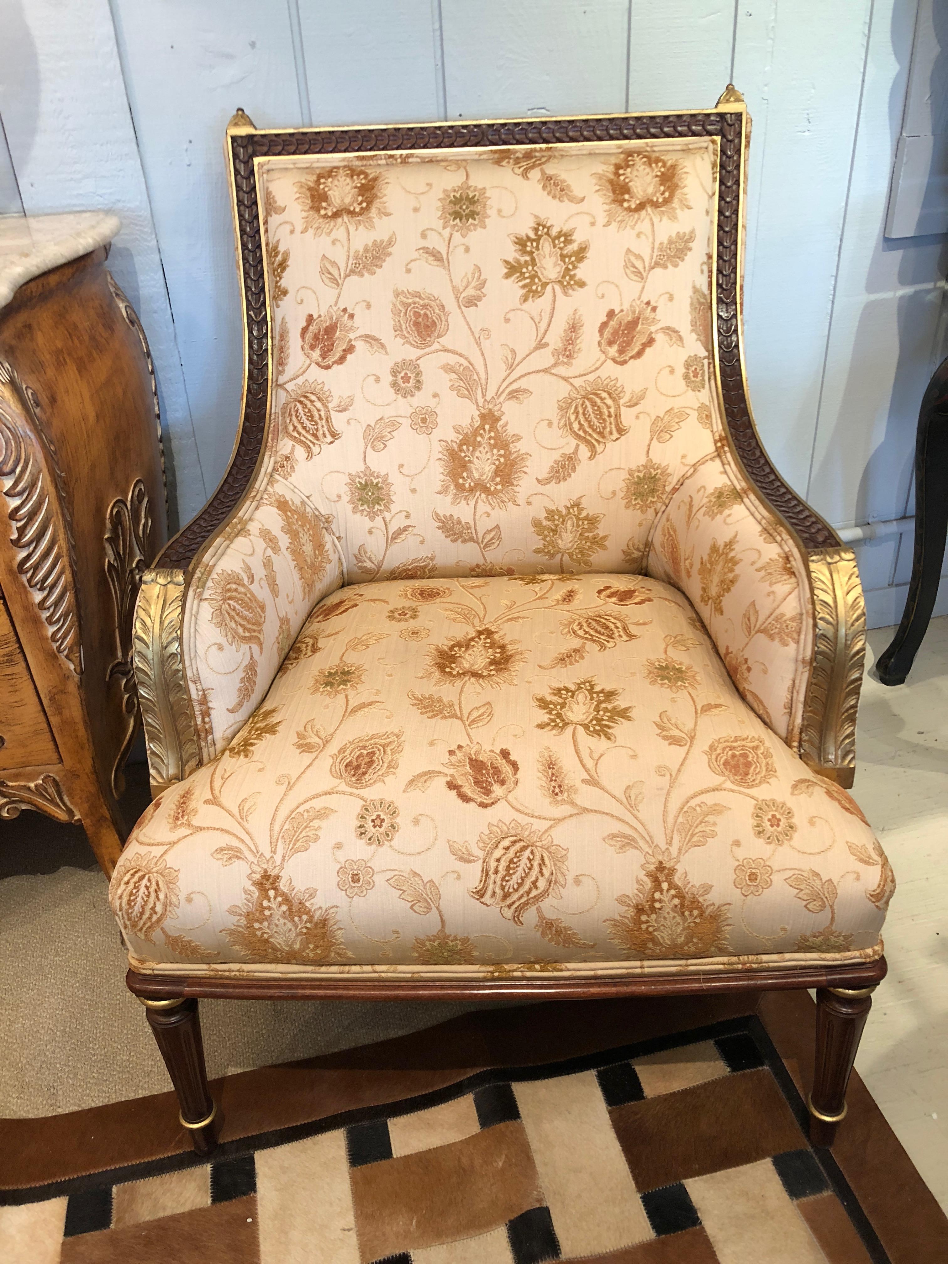 A comfortable beautifully made pair of French style bergère chairs having elaborately carved and gilded wood and pretty neutral floral upholstery in cream, brown, orange and gold.
