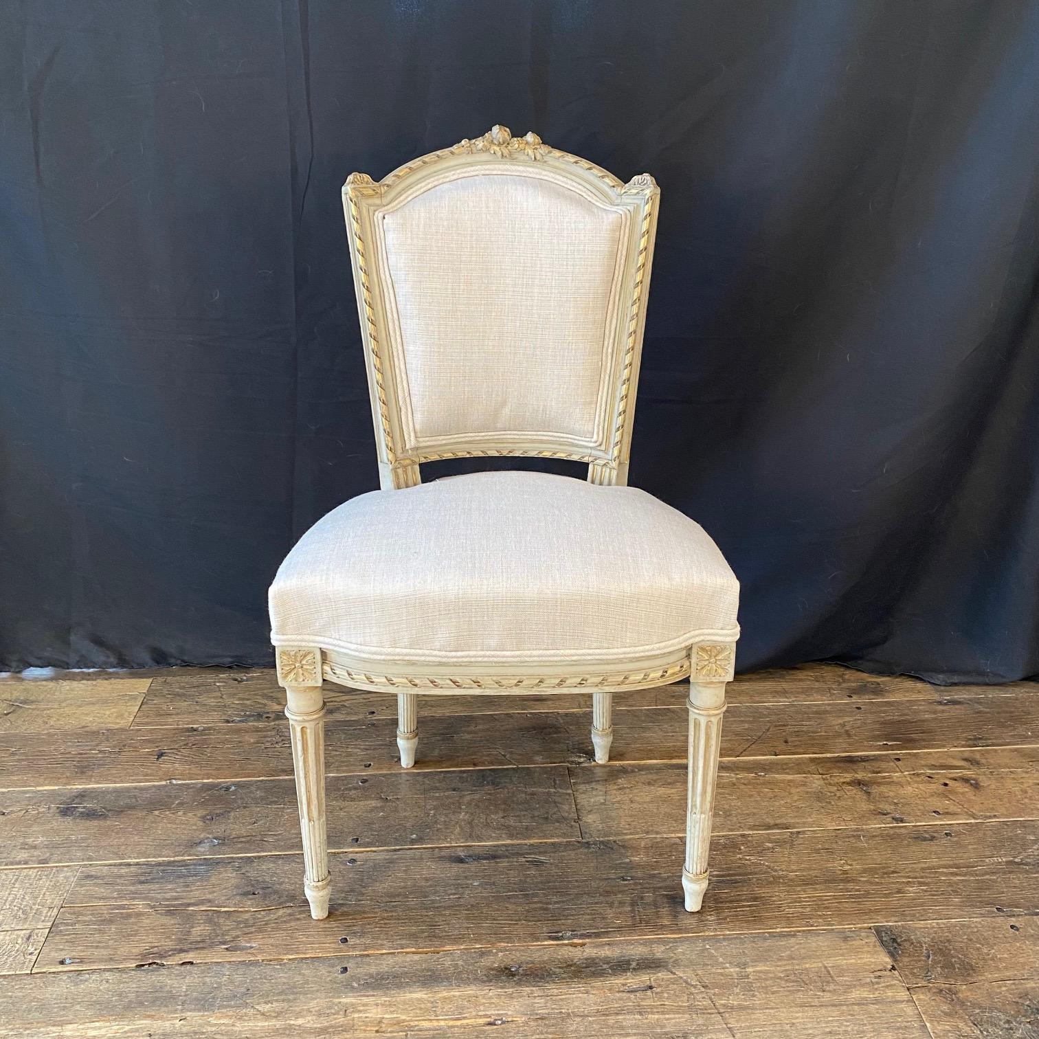 Add a touch of elegance to any room in the home with the exquisite carving on the frams of these French Louis XVI painted chairs having rectangular backs with beautifully rounded and detailed tops, fluted legs, carved rosettes and new linen