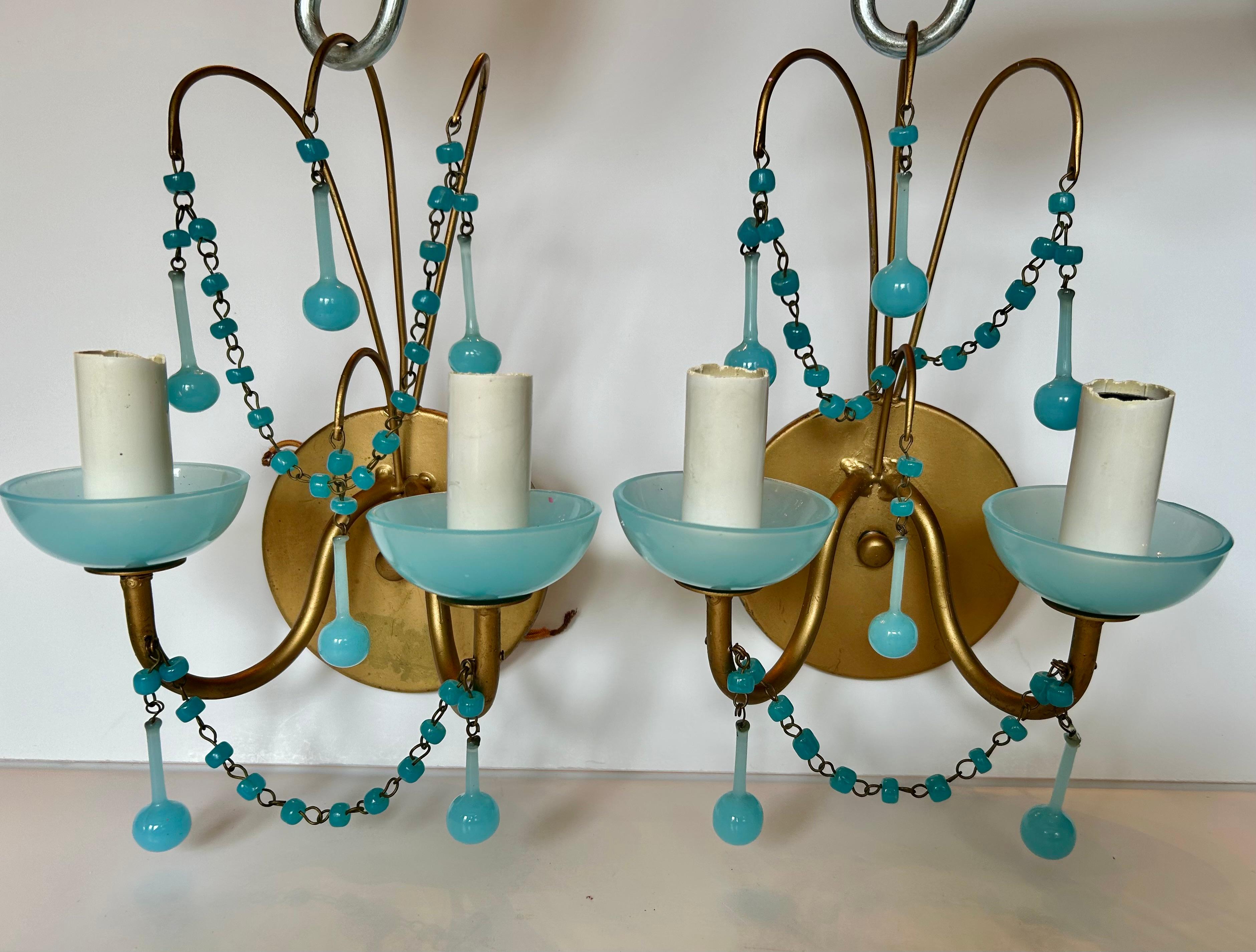 This is a  lovely pair vintage Murano glass, or opaline glass sconces in a deep aqua blue, circa 1930s. French, or possibly Italian.
Made of patinated metal and Murano glass beads and drops.
120 Volts. Each sconce with two sockets for chandelier
