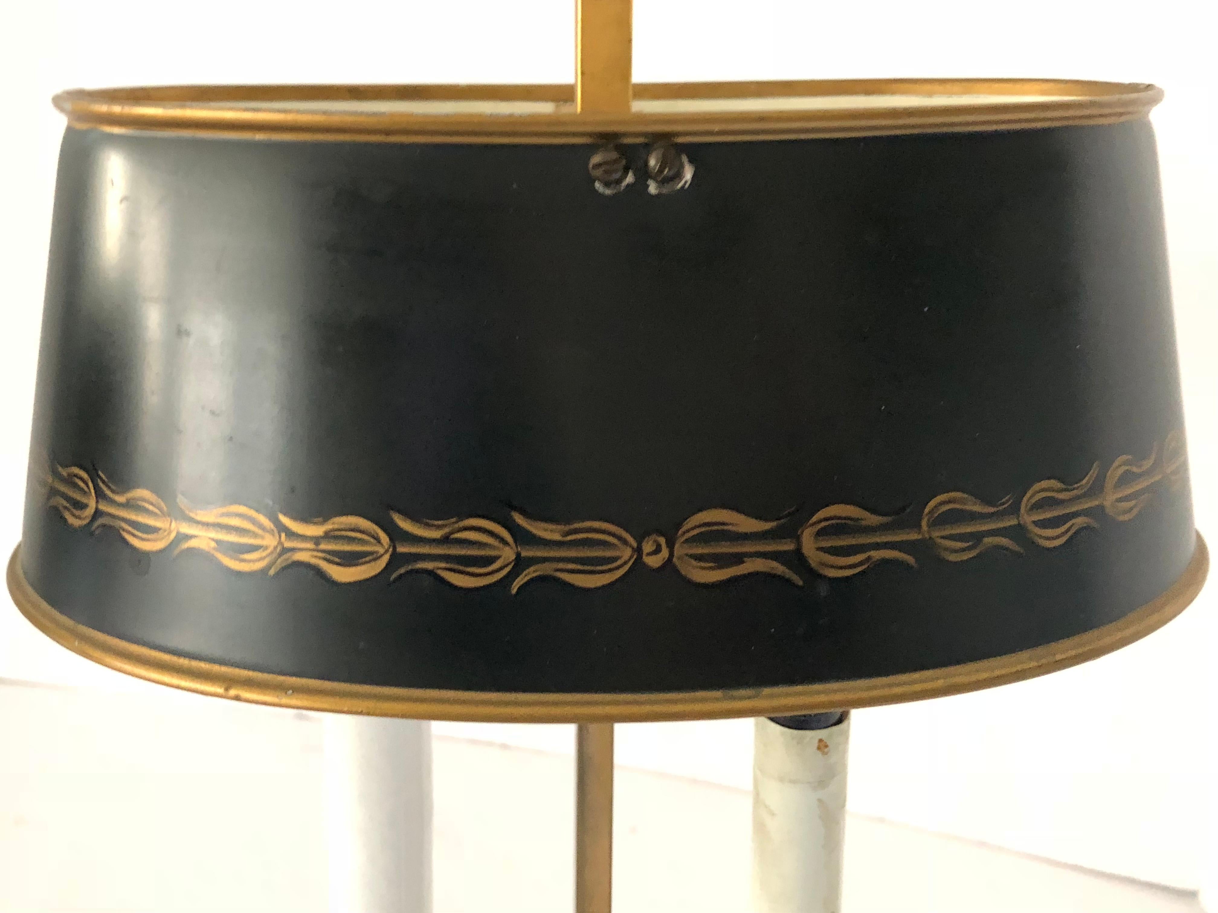 Stunning pair of French bouillotte lamps having two arms (each). The lamps are made of heavy brass that has been gold plated. They each have a black tole shade that is decorated with gold leaf around the bottom. Shades can be raised and lowered.