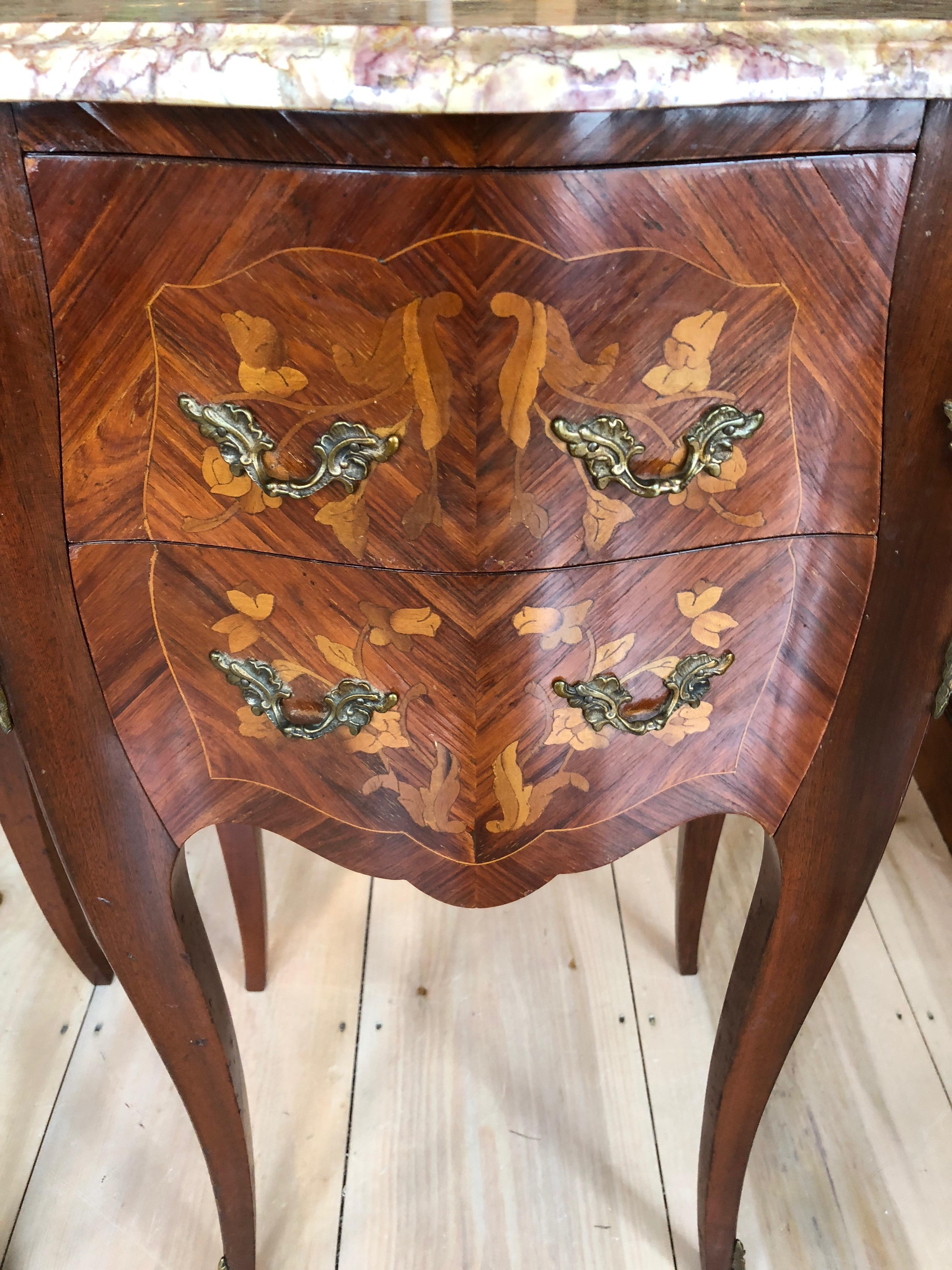 Pair of beautiful French marquetry marble-top commode nightstands with bronze ormolu mounts and original beautifully veined contoured and beveled marble tops. Fine veneering and cast bronze hardware. Two drawers in each and elegant curved legs.
 