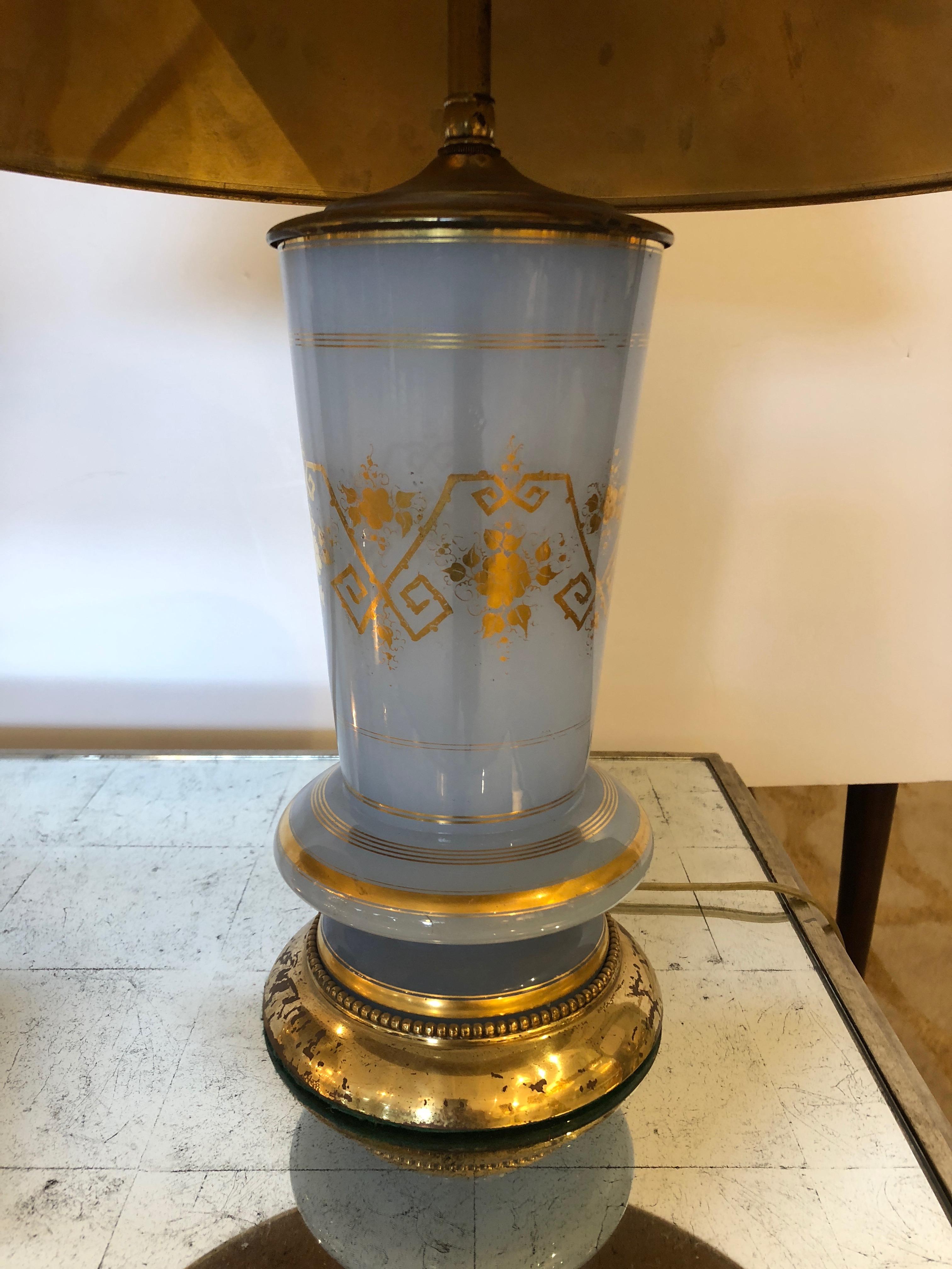 Pair of very elegant ice blue milky glass table lamps with gorgeous gold leaf decoration as well as bases. Some of the gold is chippy on the bases, and the two beautiful custom shades with gold bands top and bottom are slightly different colors, one