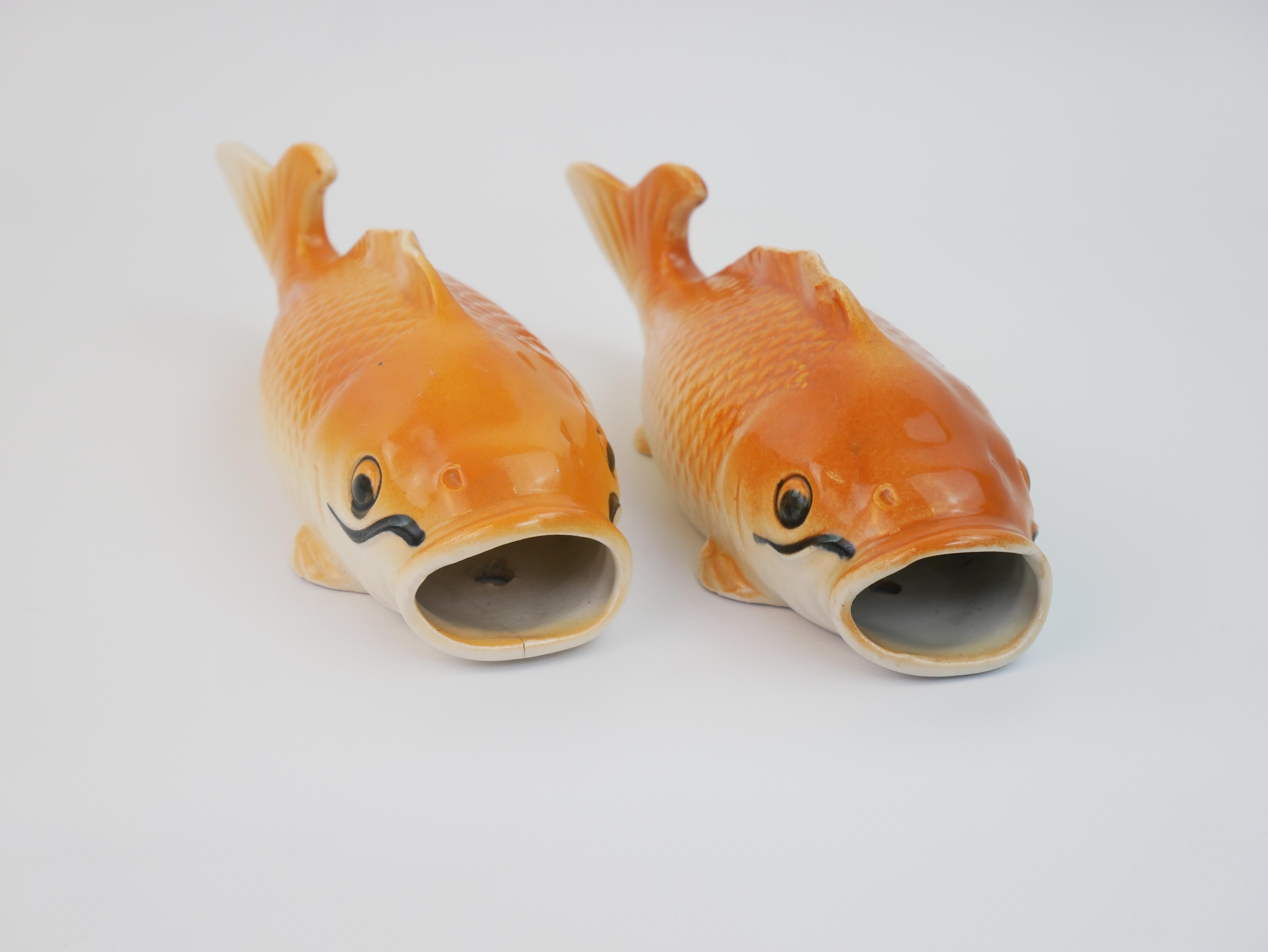 Si tratta di un'affascinante coppia di figurine di pesci in ceramica vintage degli anni '60, progettate con una funzionalità versatile per essere montate a parete o esposte su una superficie piana. Ogni pesce sfoggia uno smalto arancione e crema con