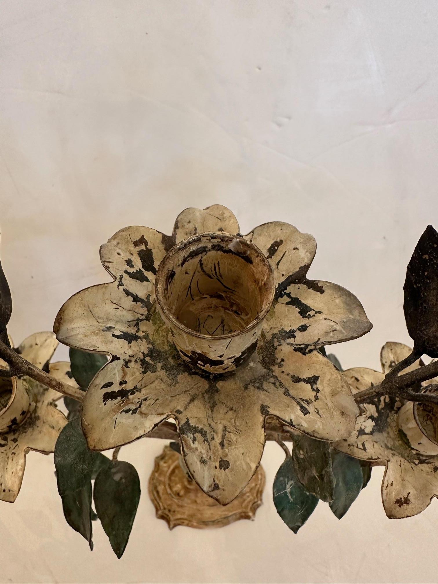 Bella coppia vintage di candelieri in metallo verniciato con foglie verdi e fiori bianchi e crema.