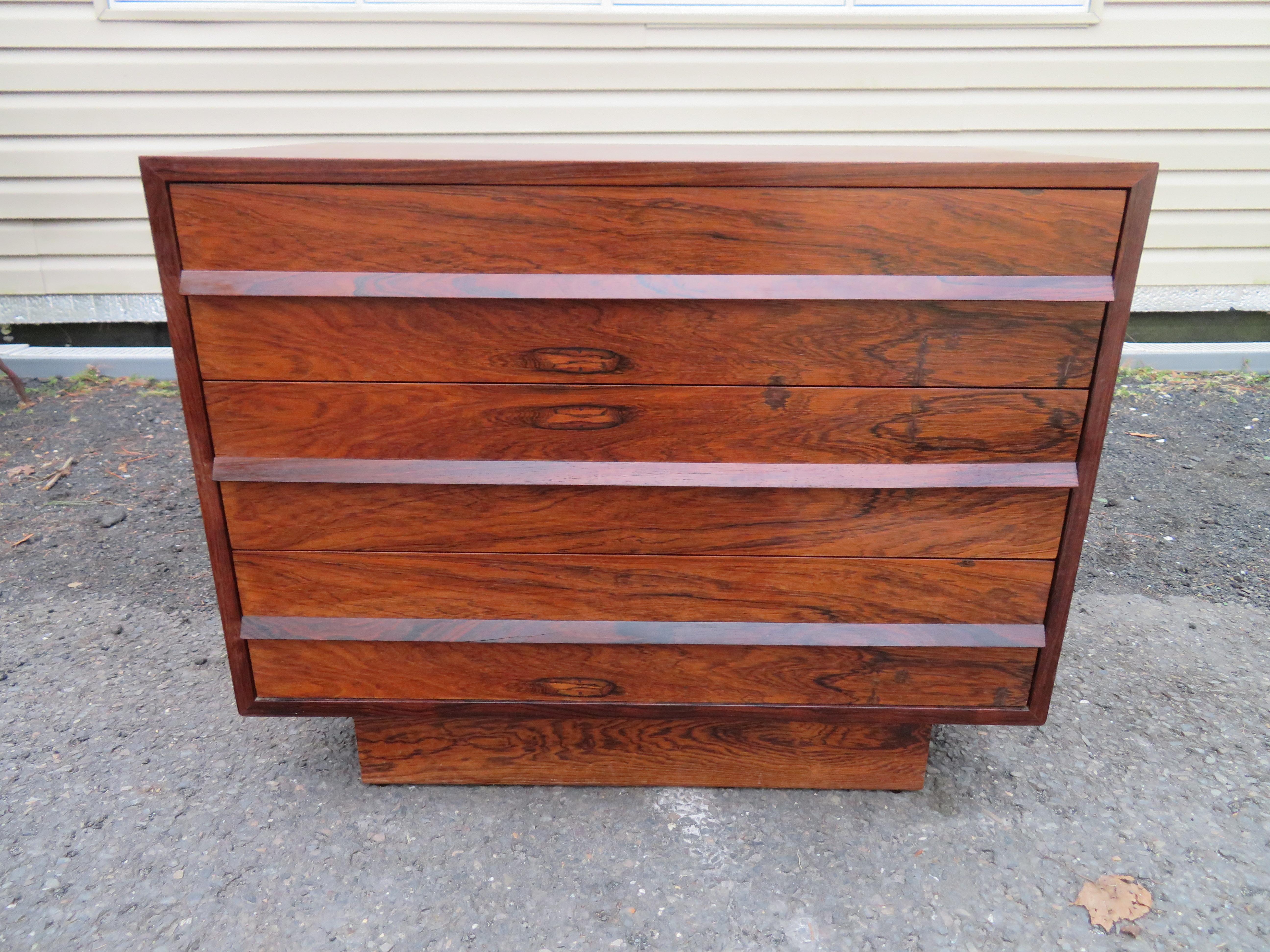 Lovely petite Danish modern rosewood bachelors chest. Rosewood veneer with solid rosewood handles. Perfectly matched drawer fronts and fully finished mahogany inside the drawers with a plinth base. Overall in excellent vintage condition with some