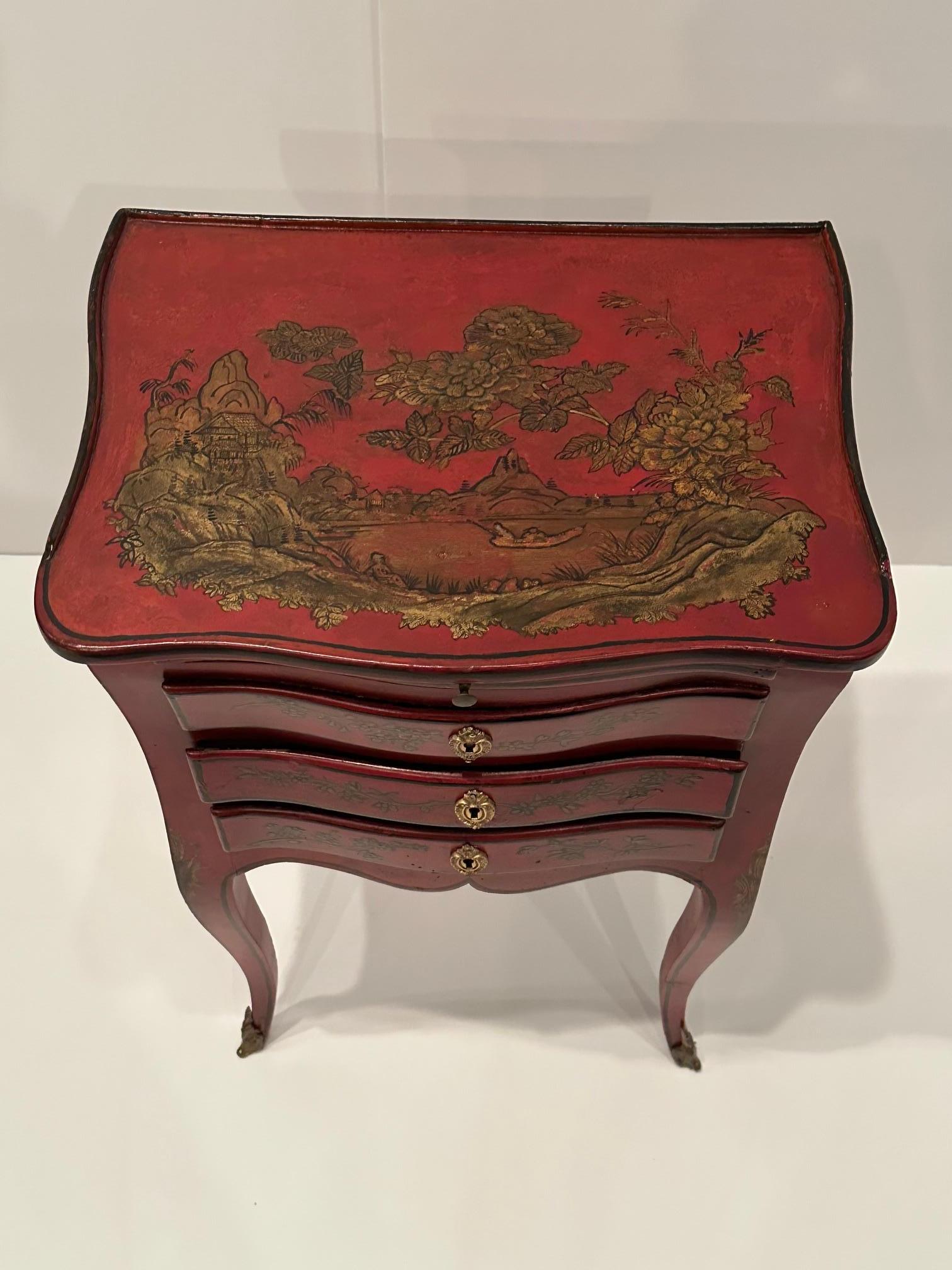 Jolie table d'appoint ou écritoire en chinoiserie française ancienne peinte à la main en rouge et or, avec d'élégants pieds cabriole se terminant par des montures en bronze.  Il y a 3 tiroirs et une glissière coulissante.
