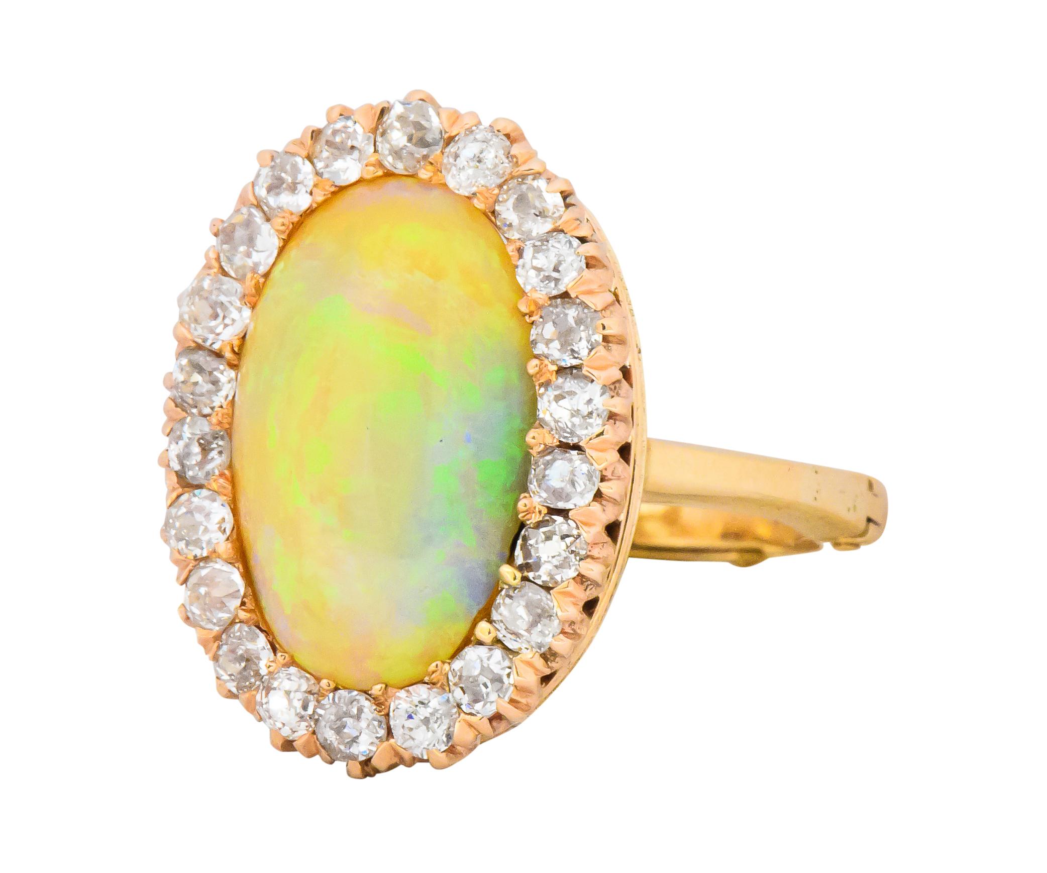 Centering a white opal measuring approximately 15.5 x 9.8 mm with good play-of-color that contains green and yellow with a bit of violet

Set within an old mine and old European cut diamond surround, with 22 diamonds weighing approximately 0.65