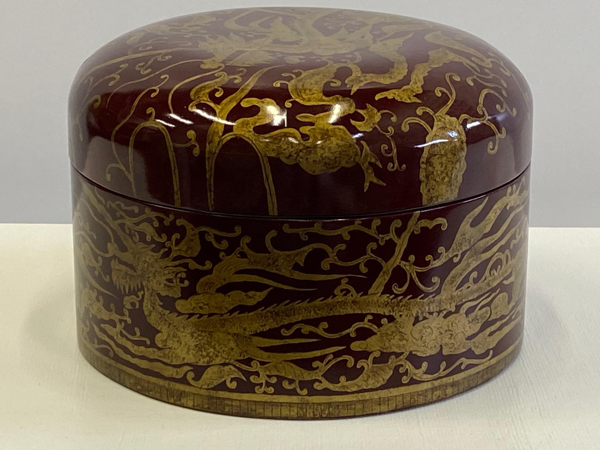 Gorgeous round jewel of a red laquered lidded box having gold Asian inspired decoration with dragons and birds.