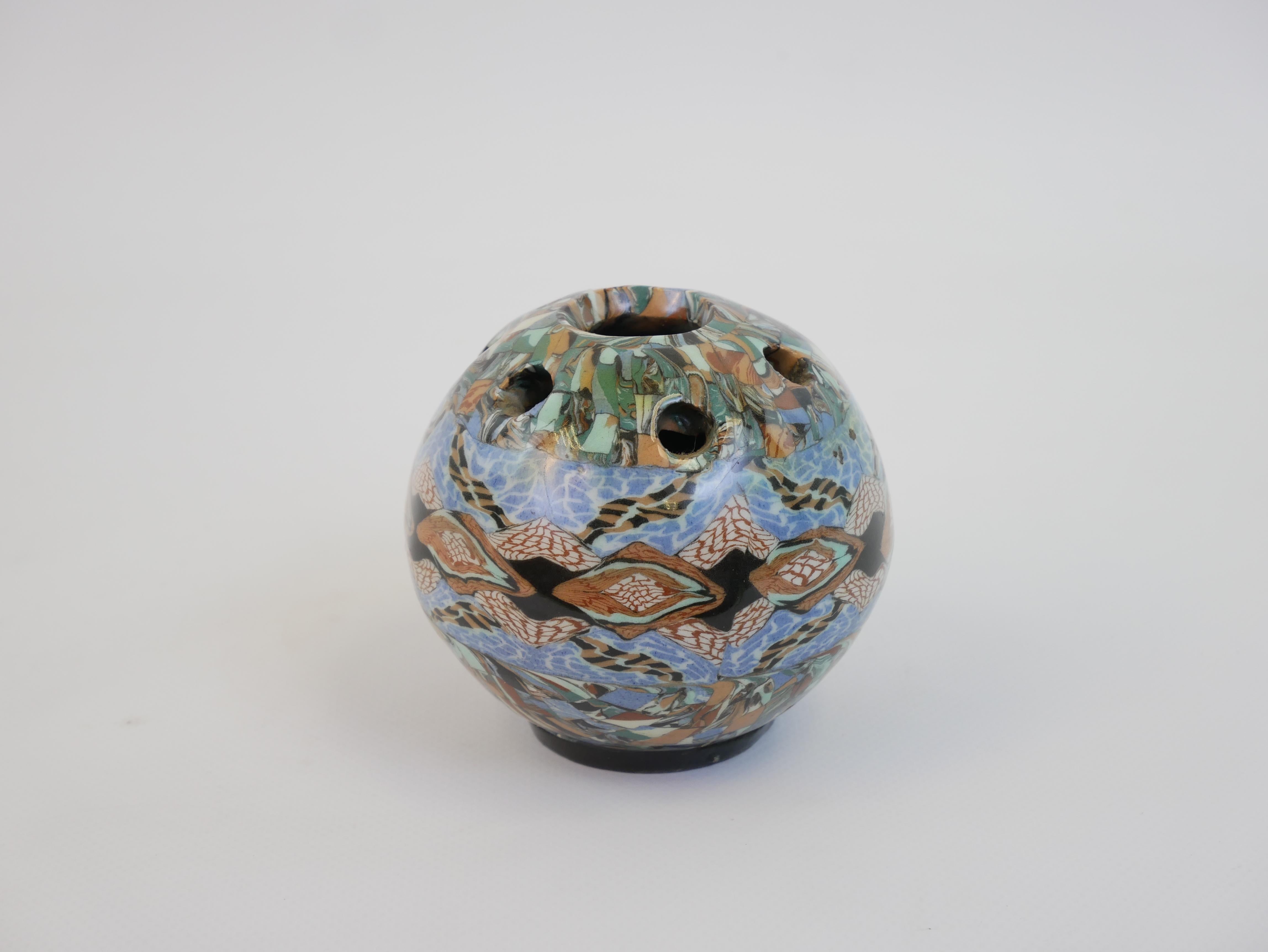 This delicate flower frog vase by Jean Gerbino is a stunning example of the artist’s mastery in terre mêlée (mixed clay) ceramics. Measuring 9 cm in diameter, this spherical vase features multiple small openings at the top, designed to elegantly