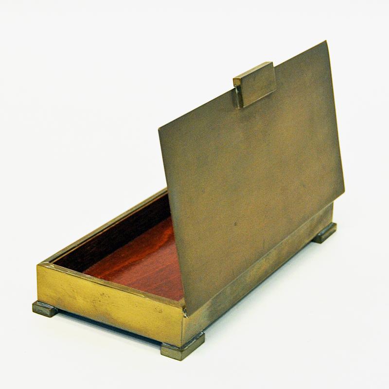 Rectangular and practical brass casket made by Ystad Metall Sweden in the 1940s. Perfect for small items like jewelry, coins, keys, cards etc. Wooden bottom plate inside the casket. Top lid of brass attached on the side. Perfect vintage patina and