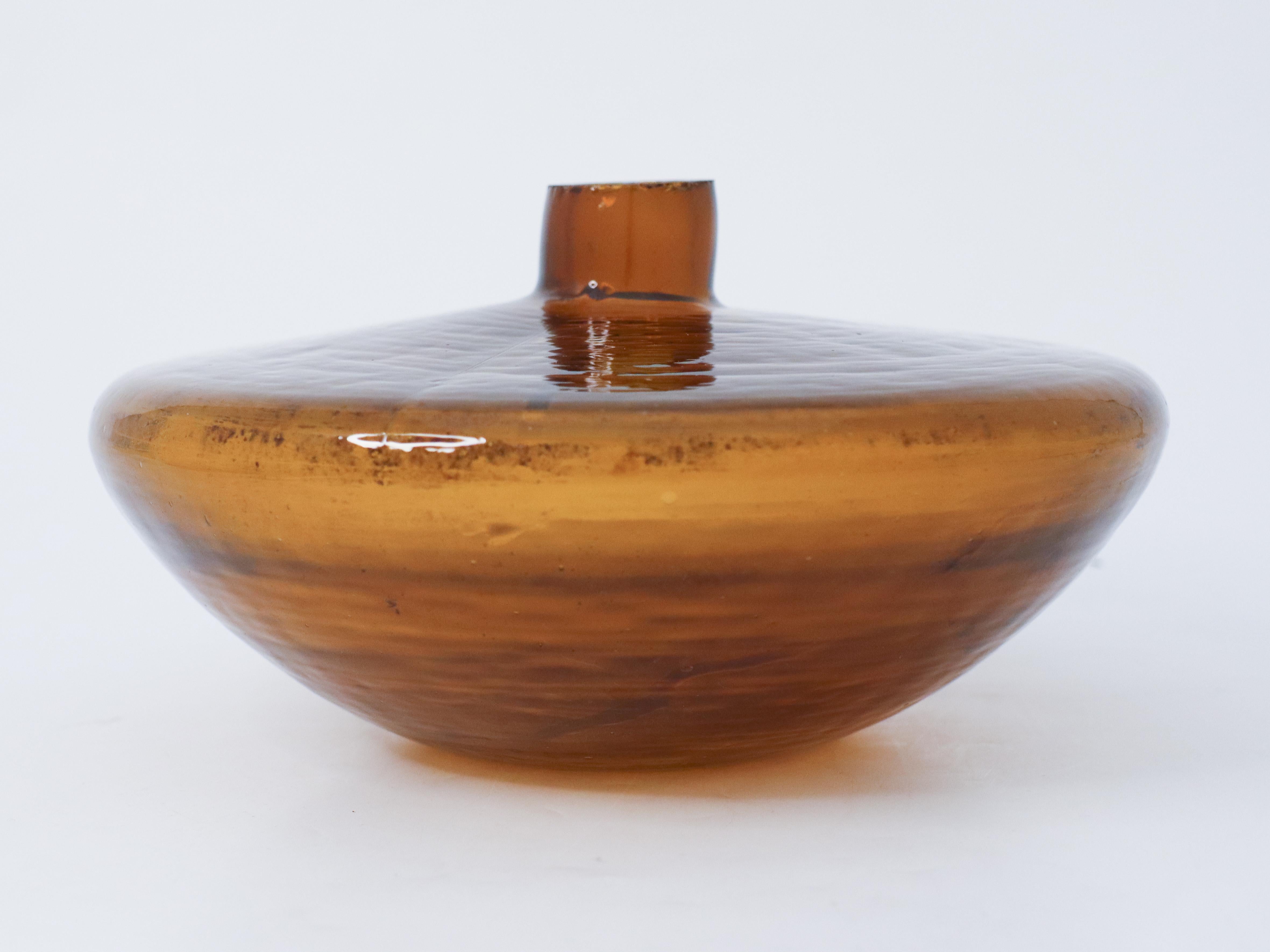 Un beau vase en verre de couleur ambrée. Il a un diamètre de 22 cm et une hauteur d'environ 12 cm. Il a une forme brute et est un peu rugueux au sommet comme vous pouvez le voir. Cette pièce a été fabriquée à l'origine comme nourrisseur d'abeilles