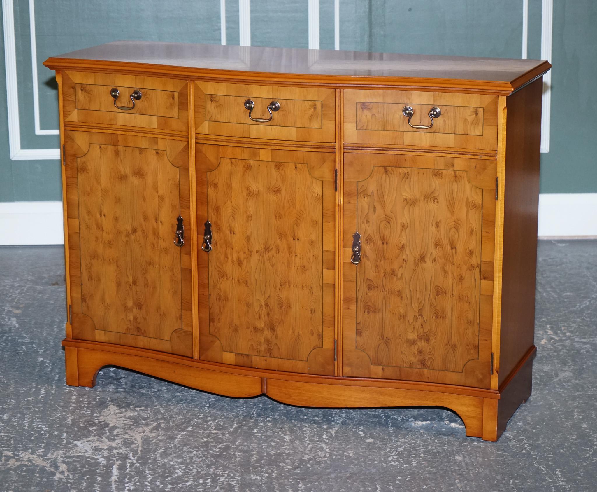 
We are delighted to Present This Lovely Vintage Burr Yew Wood Bow Front Sideboard.

A very well-made and solid sideboard, made from yew and burr yew wood.
It has been made by Strongbow furniture, It serves three drawers and three cupboards with