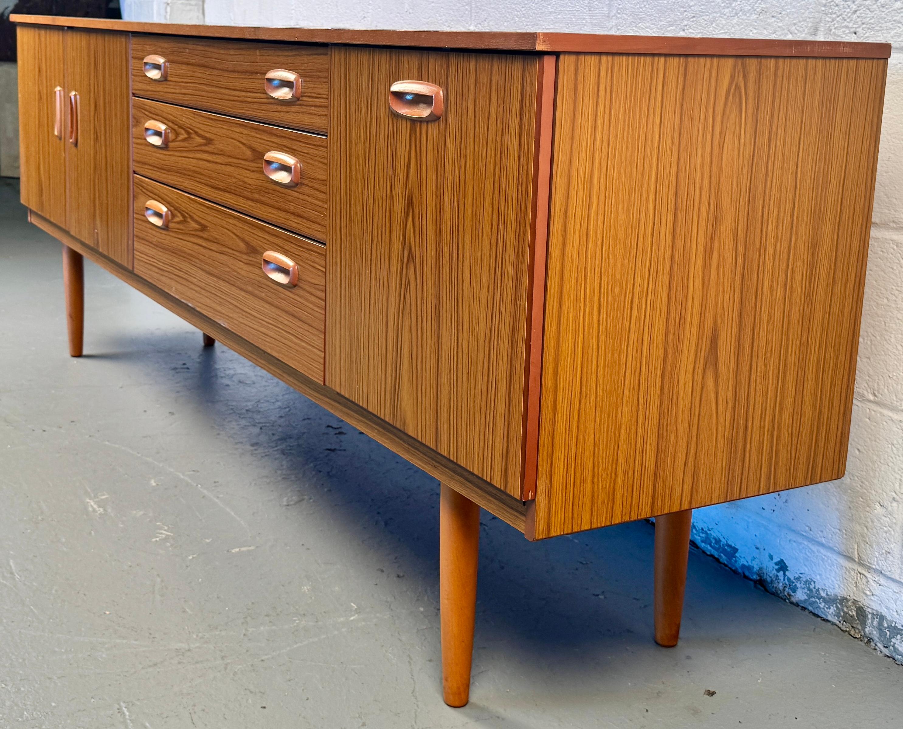 A striking example of 1960s–70s British mid-century craftsmanship, this Schreiber teak sideboard brings refined Scandinavian flair and practical storage into any space.

Please confirm location with seller (NY or NJ).