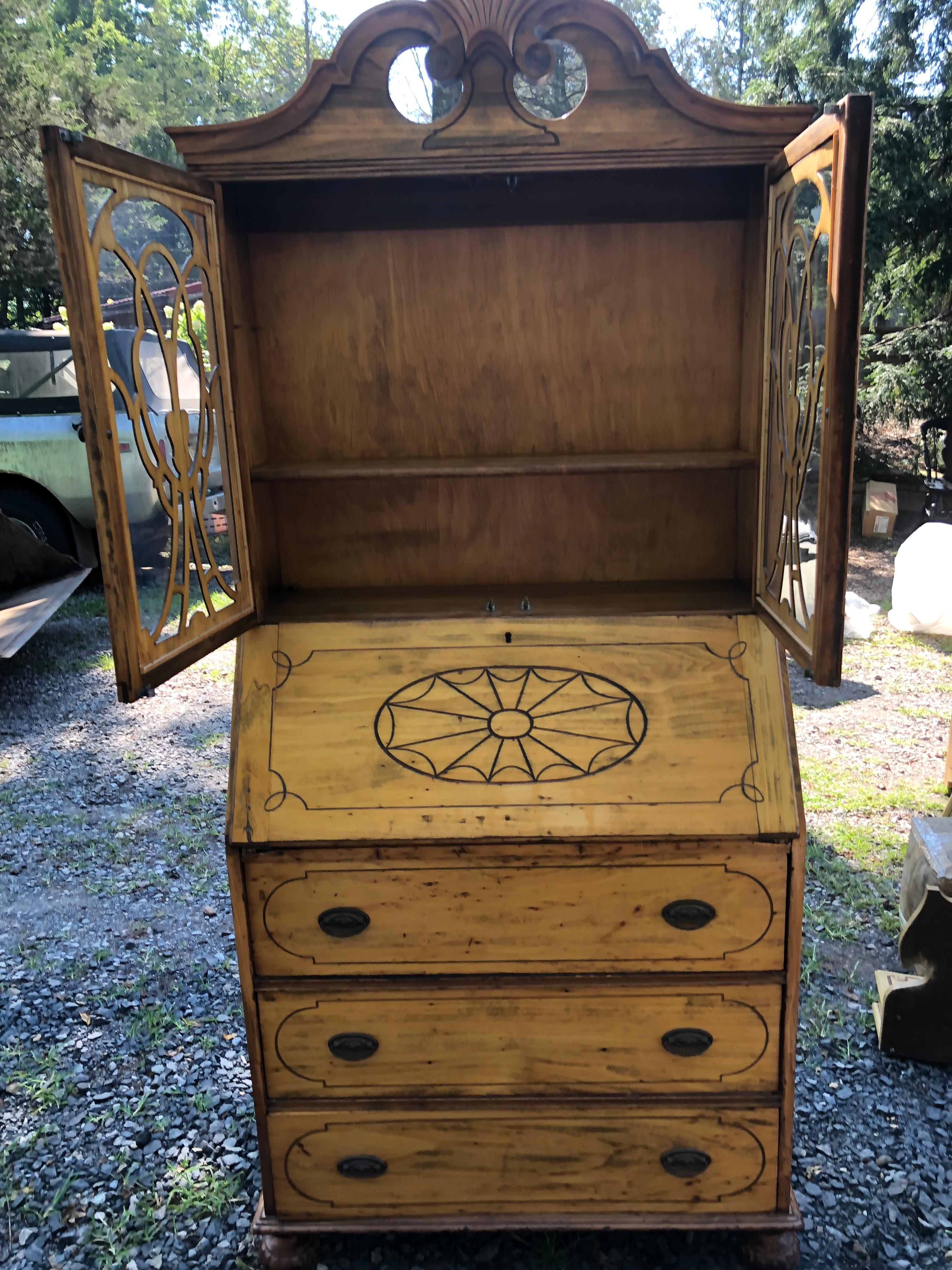 Pretty vintage American secretary cabinet having slant front desk that opens to a 29.5 d surface and cubbies with one little drawer.  The top has glass doors with shelves inside and a lovely decorative shell motif cornice.  On the bottom are 3 roomy