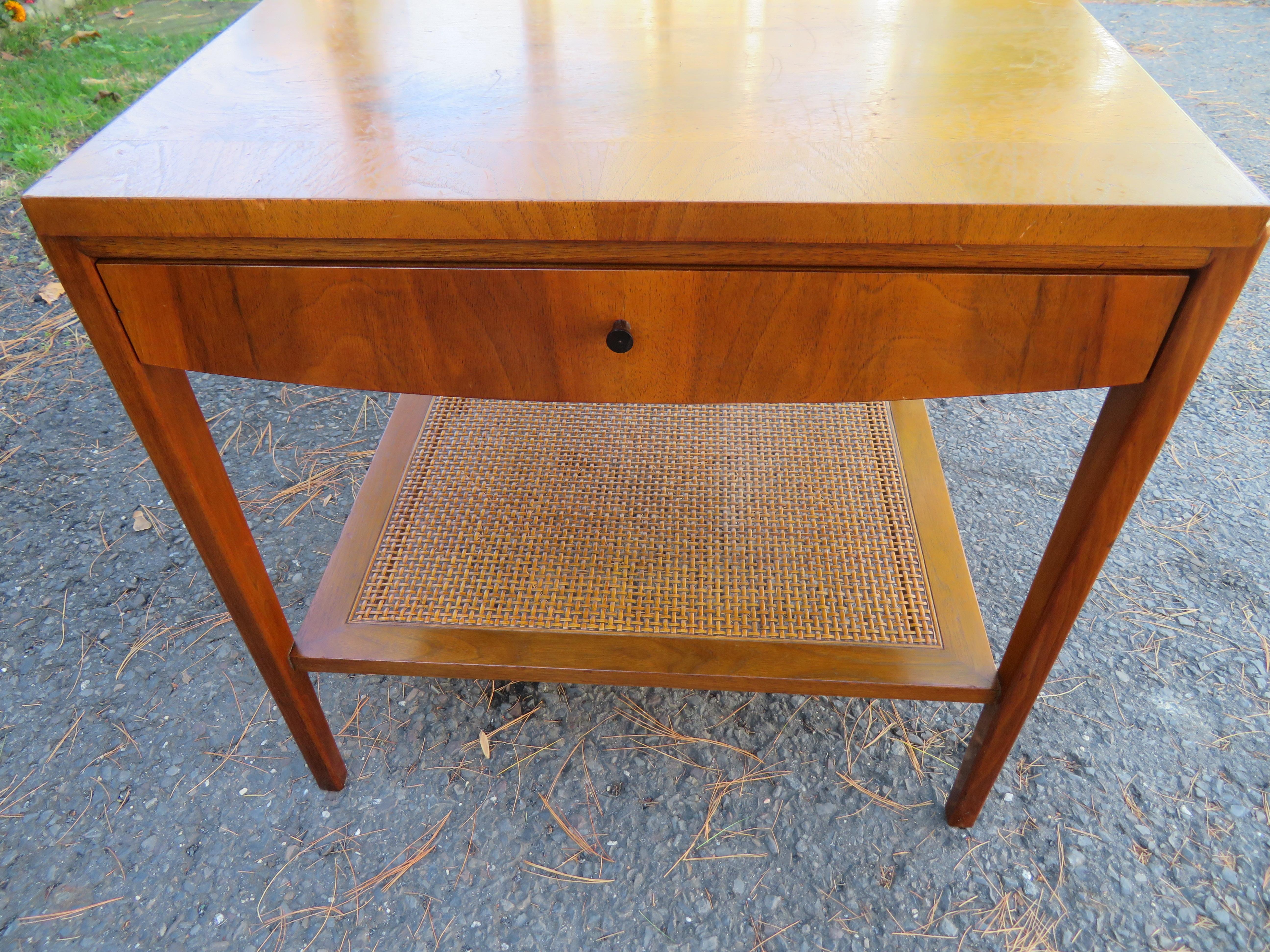 Lovely Widdicomb walnut and cane two-tier, single-drawer end table. Sleek and simple design with a floating drawer cabinet with a banded bordered top. The lower tier is caned and in wonderful vintage condition. We love to use this kind of table next