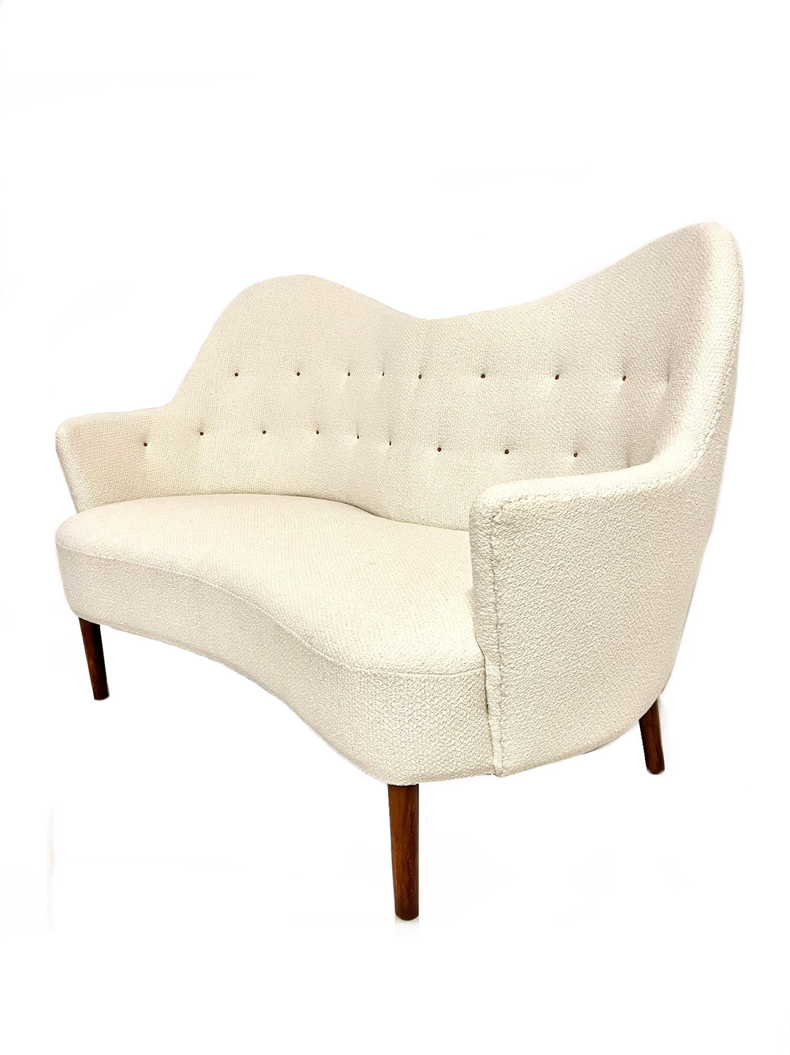 Loveseat with very curvy lines that surrounds you, by danish cabinet maker in the 1940’s. It has stained beech legs and upholstered in white bouclé, and the buttons are made of coreleather. It is upholstered on both sides, which makes it able to be