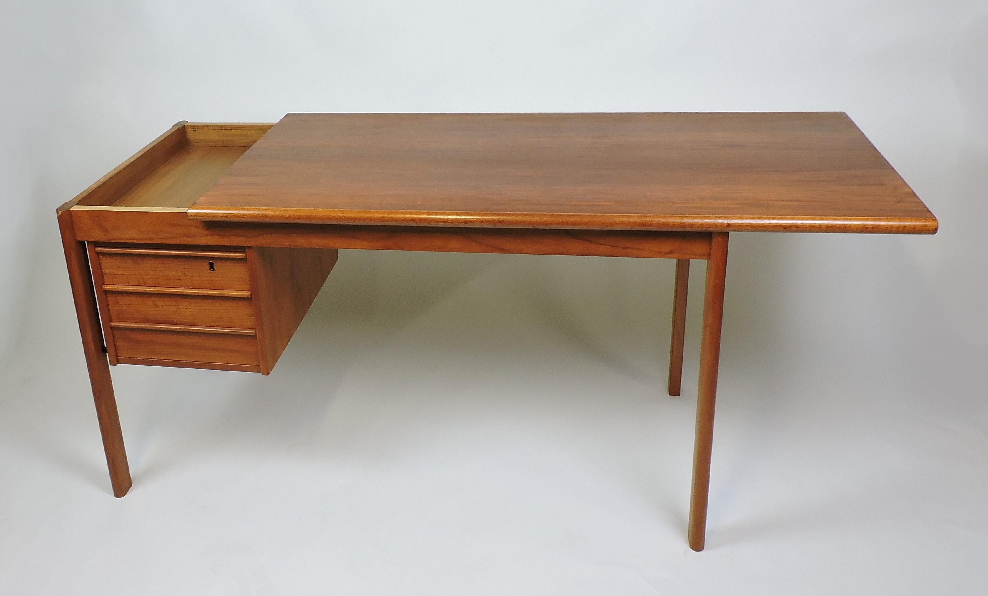 Cleverly designed teak desk designed by Peter Lovig Nielsen and made in Denmark. This desk has a top that slides open to reveal two hidden compartments and three drawers including one that locks. A key is included. Labelled and stamped, Lovig,