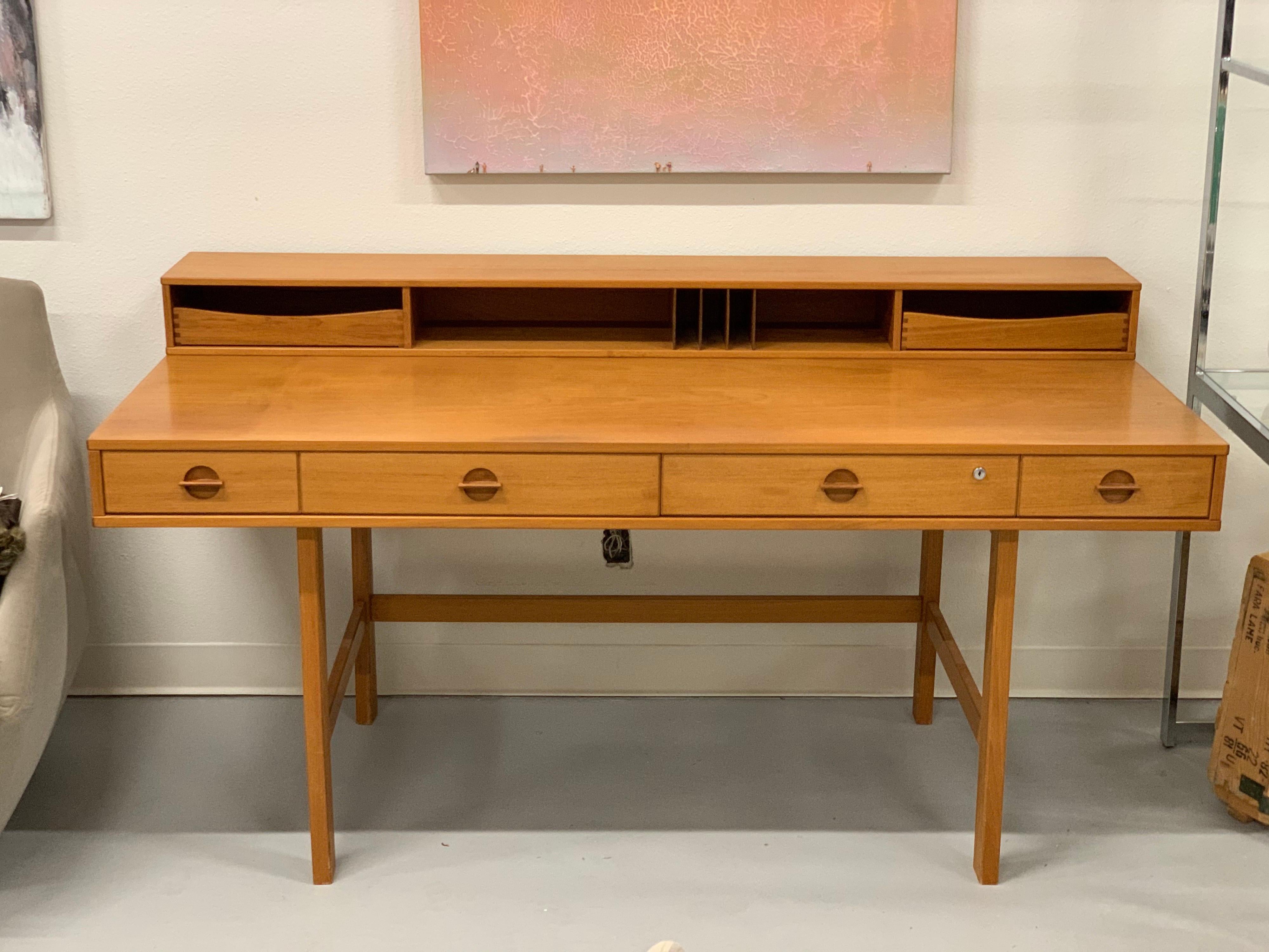 A vintage Scandinavian teak desk by Peter Lovig Nielsen from the 1970s. It has been described as being designed by Jens Quistgaard. The top back flips over and lies flat to increase the surface area. The piece is in original condition and has some