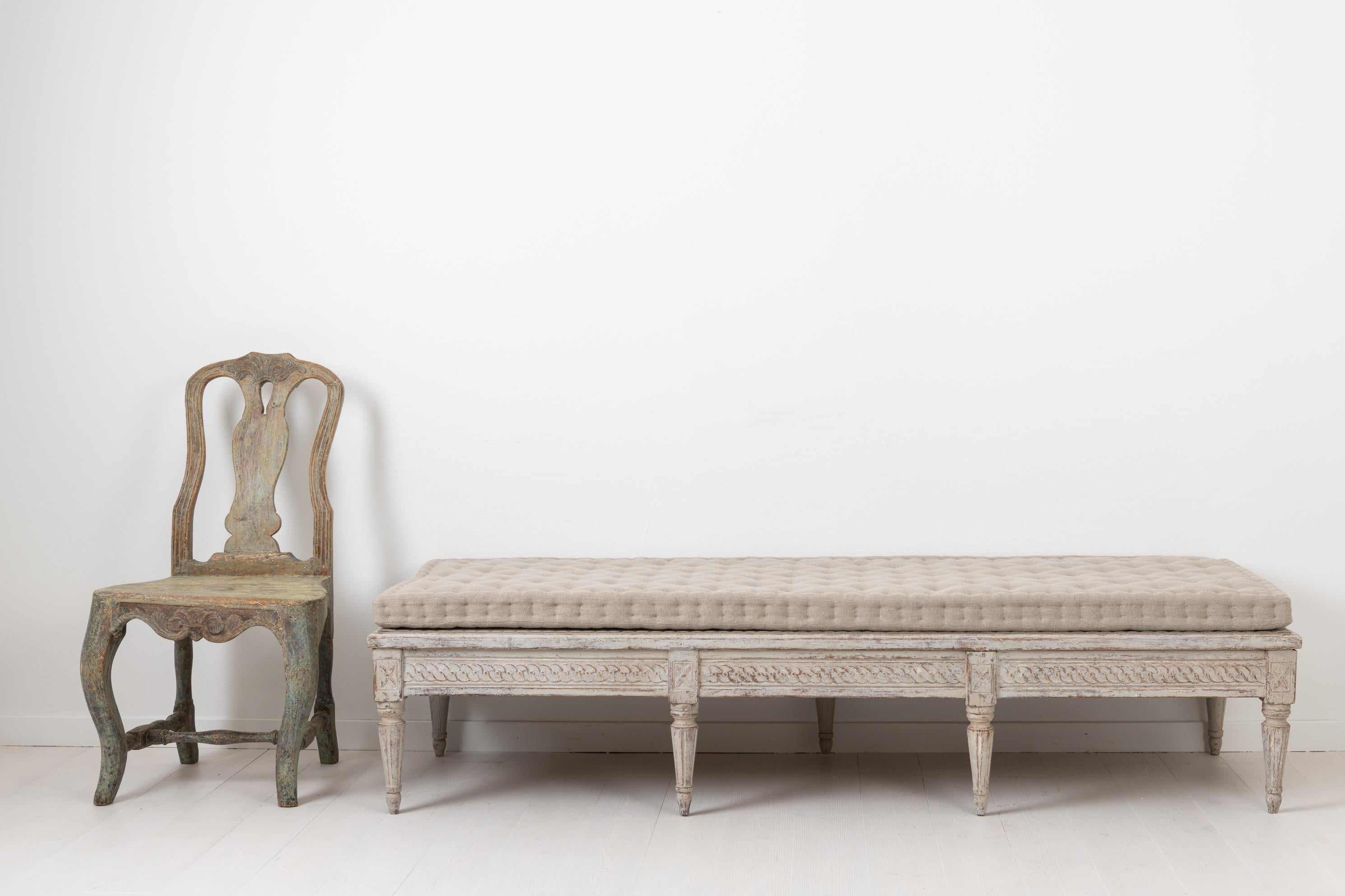 Low Gustavian bench made around the turn of the century, 1700-1800. The Gustavian bench is Swedish and made in pine. The light grey or white paint is distressed with hints of wood showing trough which highlights the decor and gives the bench that