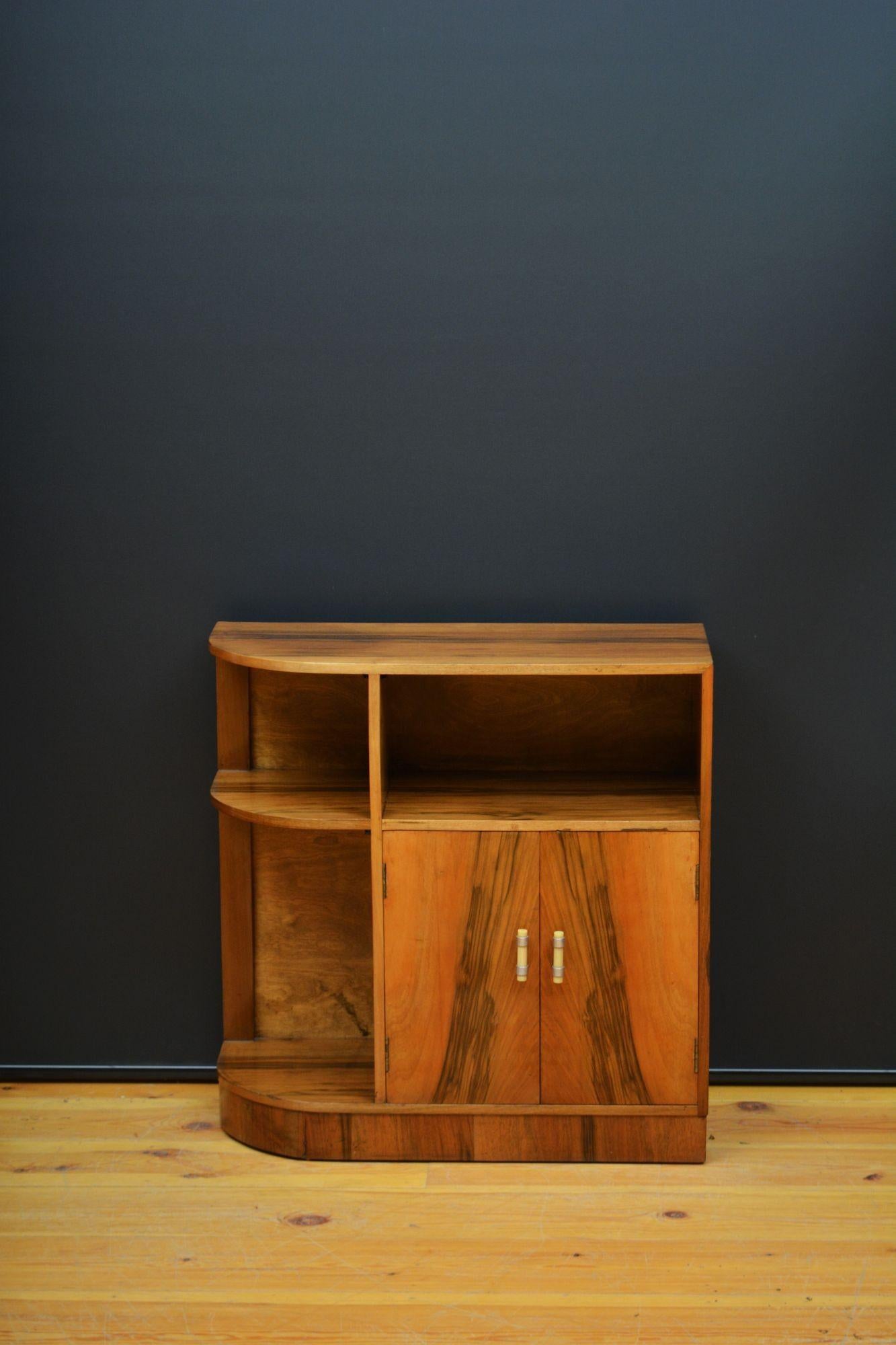Sn5698 Stylish Art Deco side cabinet, having well figured top with one curved side, open storage section and a pair of well figured cupboard door enclosing removable shelf, all fitted with original Bakelite handles, all standing on plinth base. This