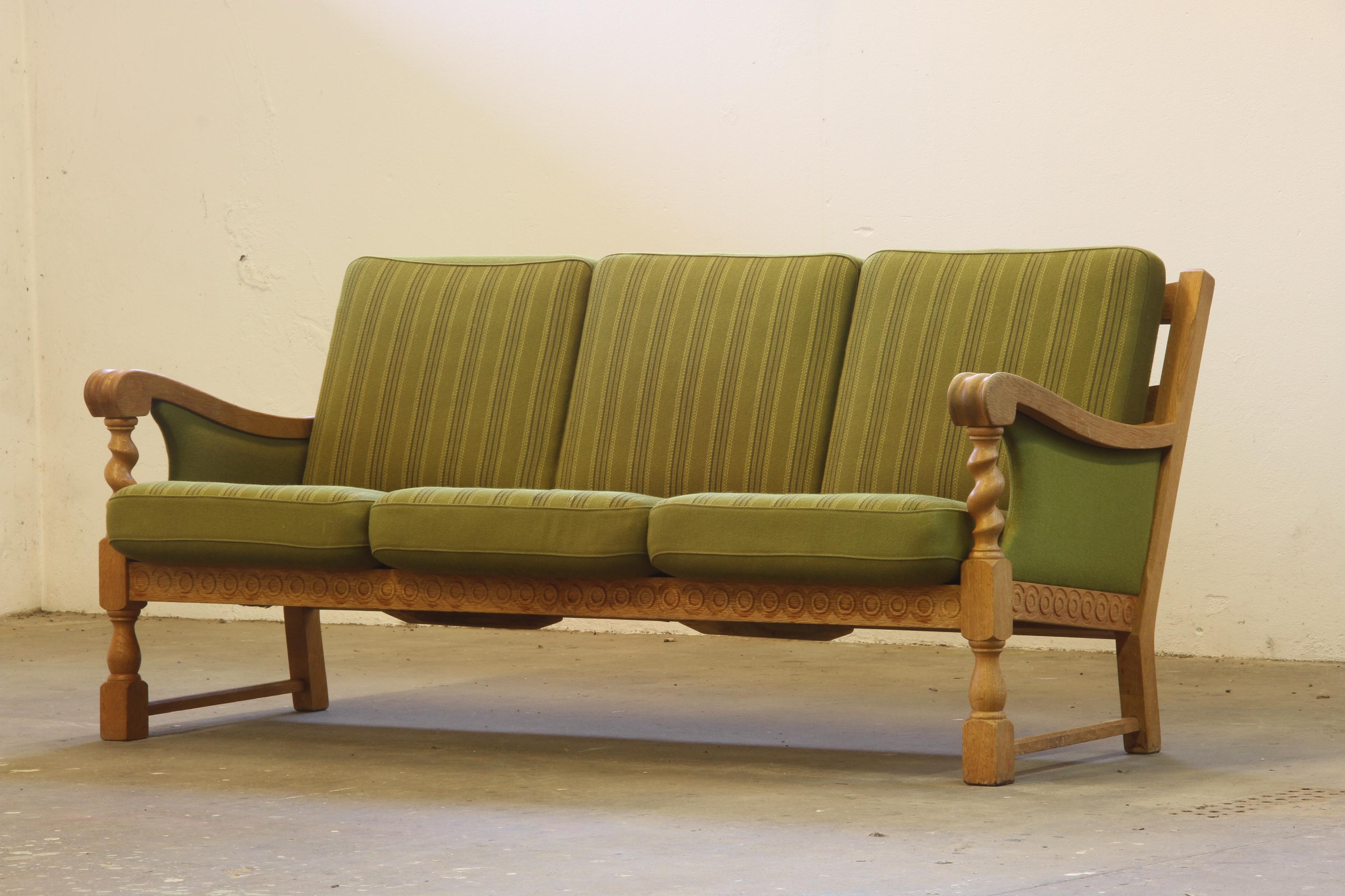 A beautiful 3-seater sofa resembling the style of Henning Henry Kjærnulf, forms a rare sculptural find. This sofa, crafted from oak and retaining their original savak wool upholstery. Created by an unknown Danish Cabinetmaker. Mid-century