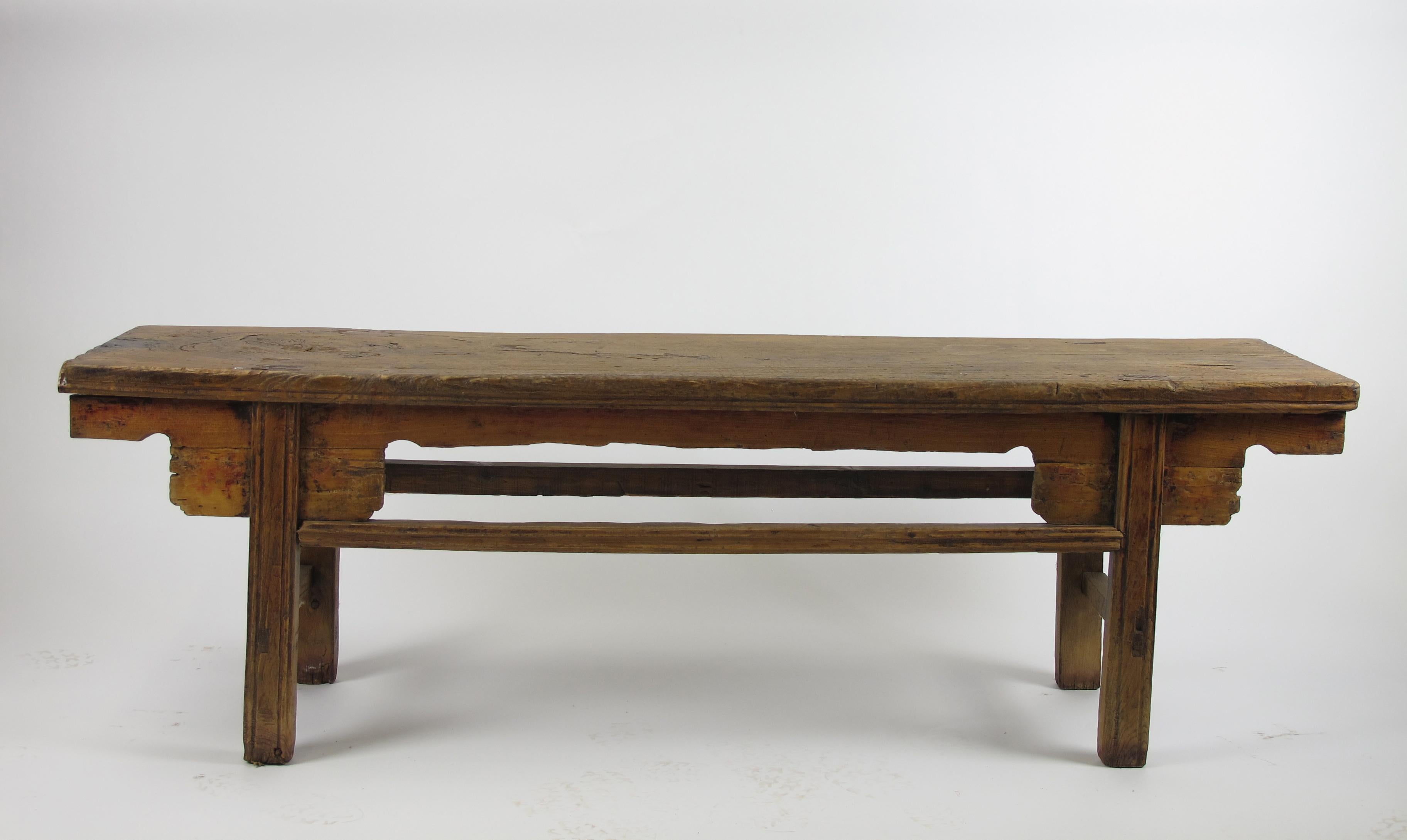 The top of this antique Chinese farmer’s bench is made of one solid piece elm with a large swirling wood knot. It shows natural aged warm color, lines, wood knots, and traditional exposed joints. It was used as a bench by the farmer’s family from