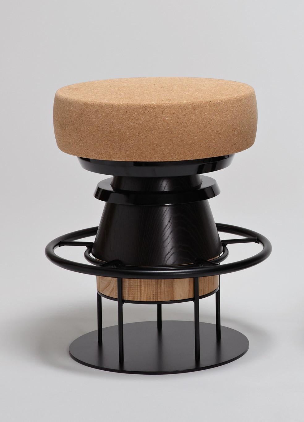 Low black tembo stool, note design studio.
Dimensions: D 36 x H 46 cm.
Materials: Lacquered steel structure, solid wood (beech) and lacquered MDF, natural cork base.
Available in colorful version and in 3 sizes: H46, H64, H76 cm.

Tembo is a