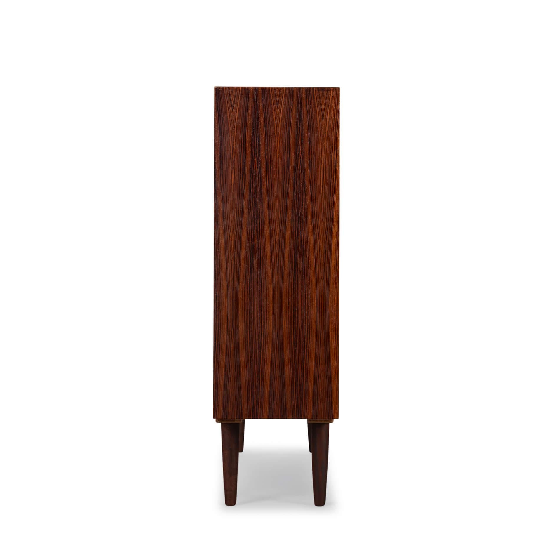 Danish low bookcase in beautiful expressive hardwoodveneer. Designed by Carlo Jensen and made by Hundevad & Co. 

This bookcase is in very good vintage condition and has a total of 6 height-adjustable shelves. Fout shelves made of wood and two
