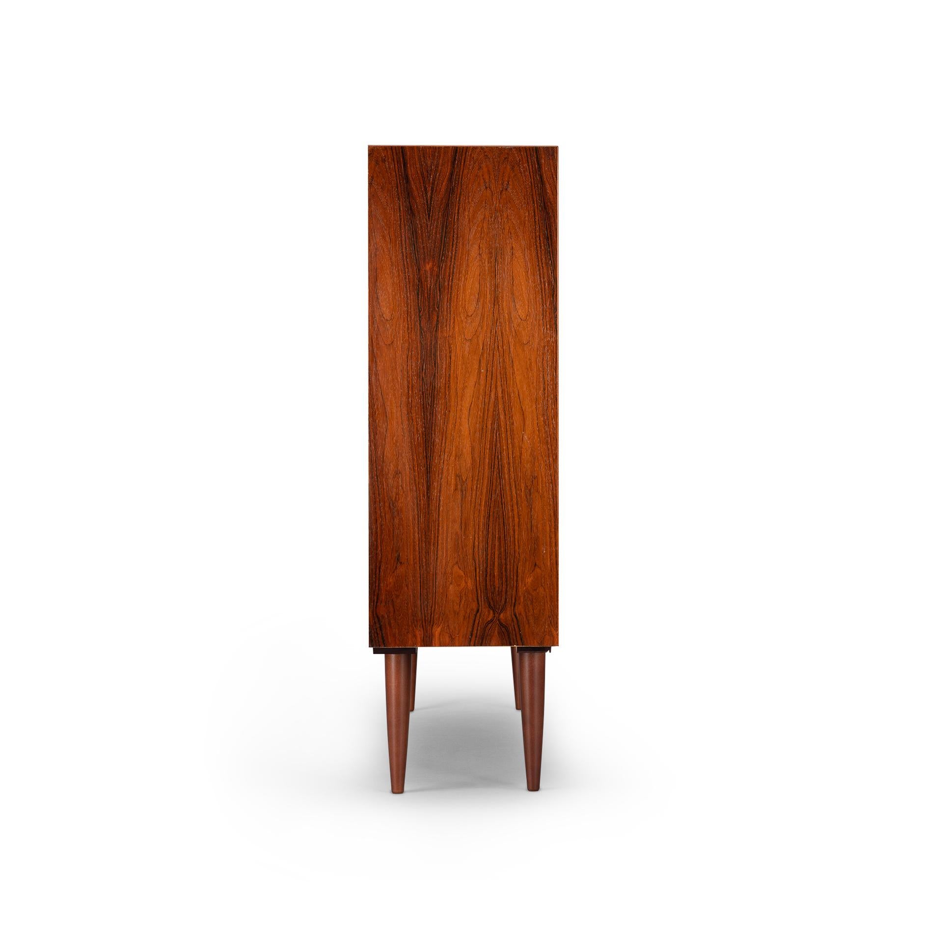 Danish low bookcase in beautiful expressive mahogany veneer. Designed by Carlo Jensen and made by Hundevad & Co. This bookcase is in very good vintage condition and has a total of 4 height-adjustable shelves.